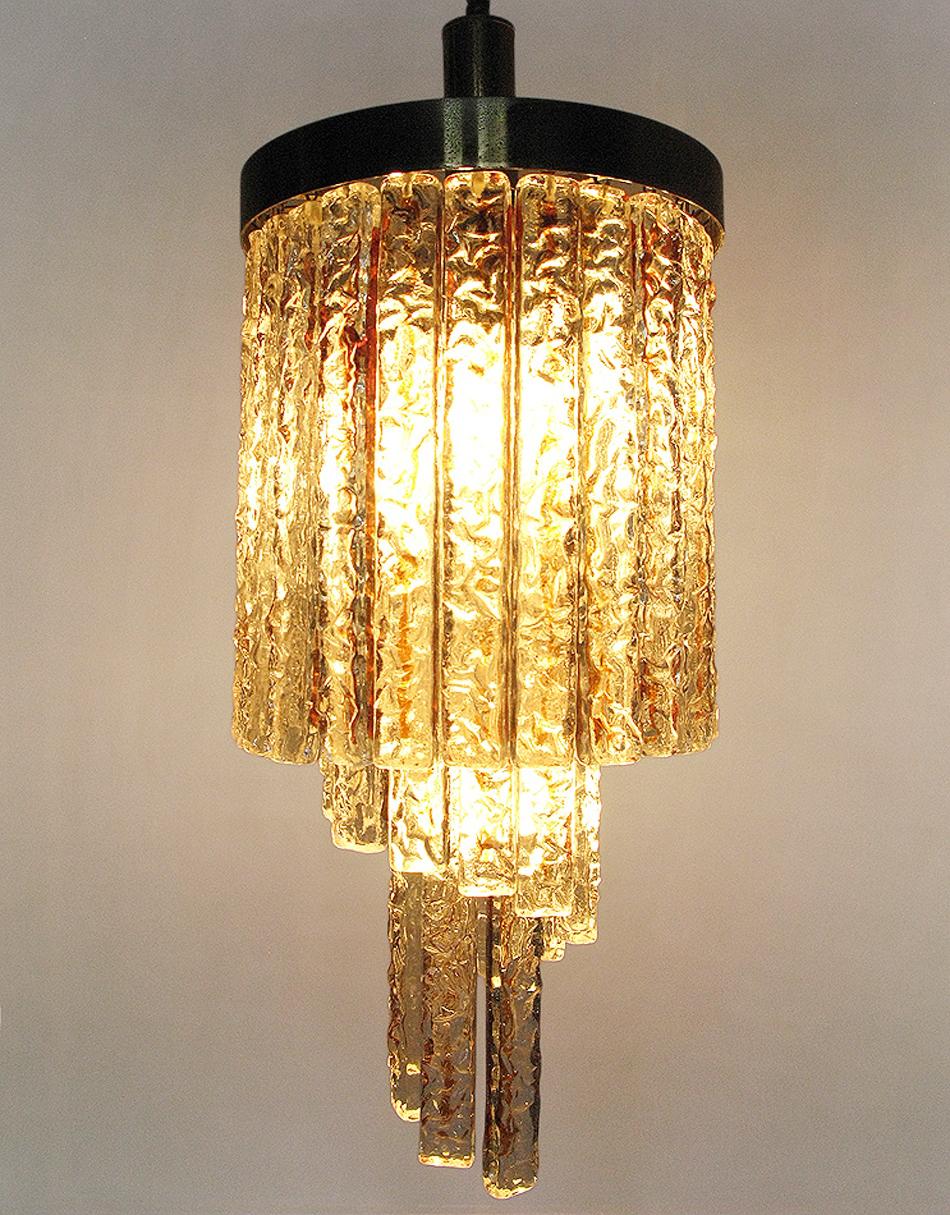 Höhe: 55cm, Fallhöhe: 110cm, Durchmesser: 27cm

Ein spiralförmiger Kronleuchter aus Murano-Glas und Messing aus den 1950er Jahren von der italienischen Firma Mazzega.

Sie besteht aus dicken Glasstücken, in deren Mitte sich ein bernsteinfarbener