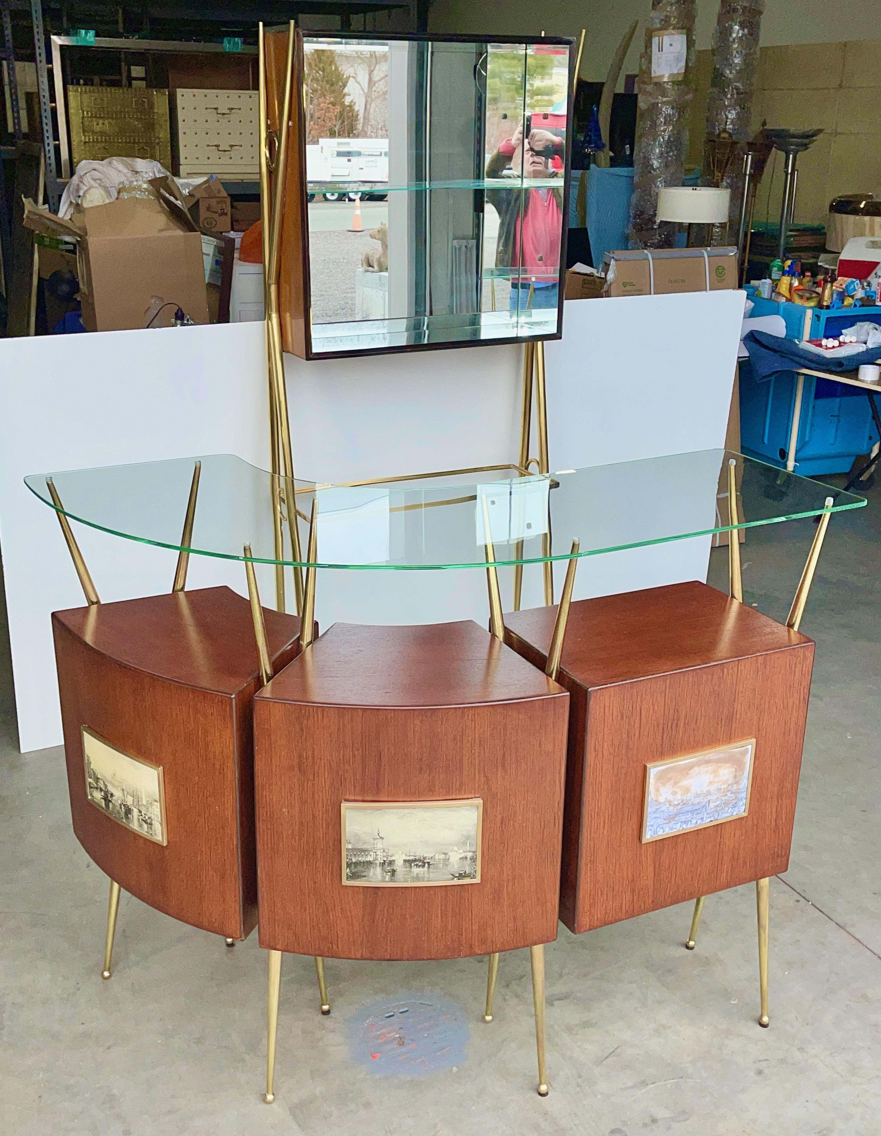 Paradigmatic 1950s Italian design emblematic of La Dolce Vita, floating bar and giraffe like back-bar consisting of case units in walnut veneer held aloft by angular tapered tubular brass scaffolds.
Standing bar has three open cabinets and a curved