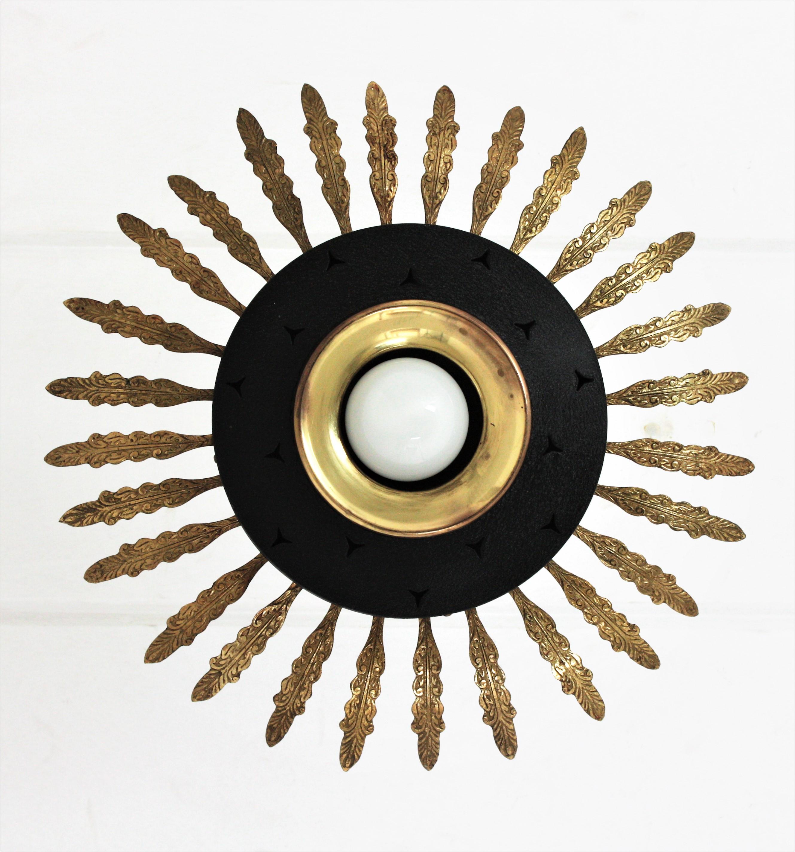 Mid-Century Modern black lacquered metal and brass sunburst suspension light, chandelier or light fixture, Italy, 1950s.
This eye-catching ceiling lamp features a black lacquered metal shade surrounded by brass leaves with foliate and scroll