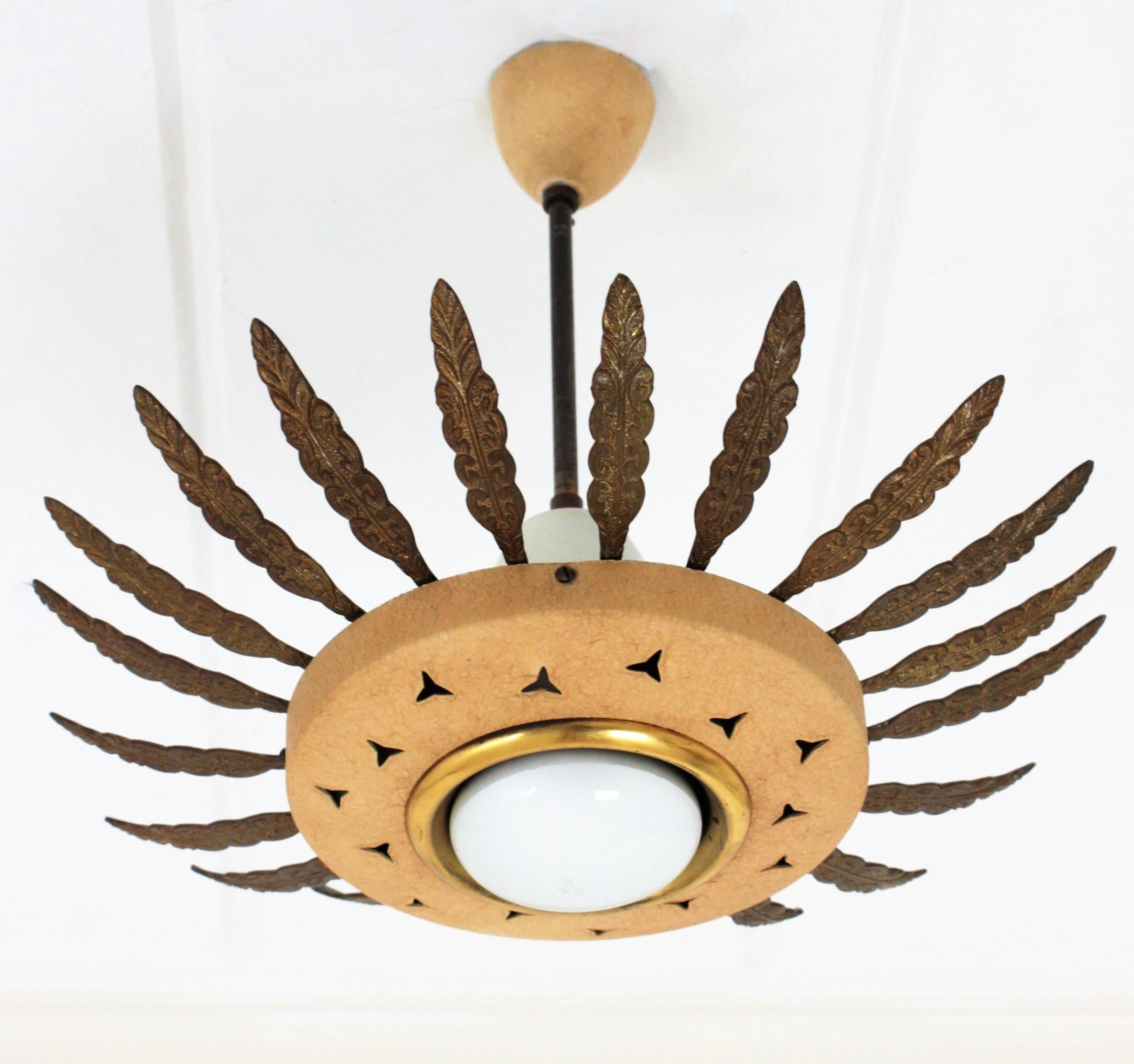 Mid-Century Modern beige lacquered metal and brass sunburst suspension light, chandelier or light fixture. Italy, 1950s.
This eye-catching ceiling lamp features a beige lacquered metal shade surrounded by brass leaves with foliate and scroll
