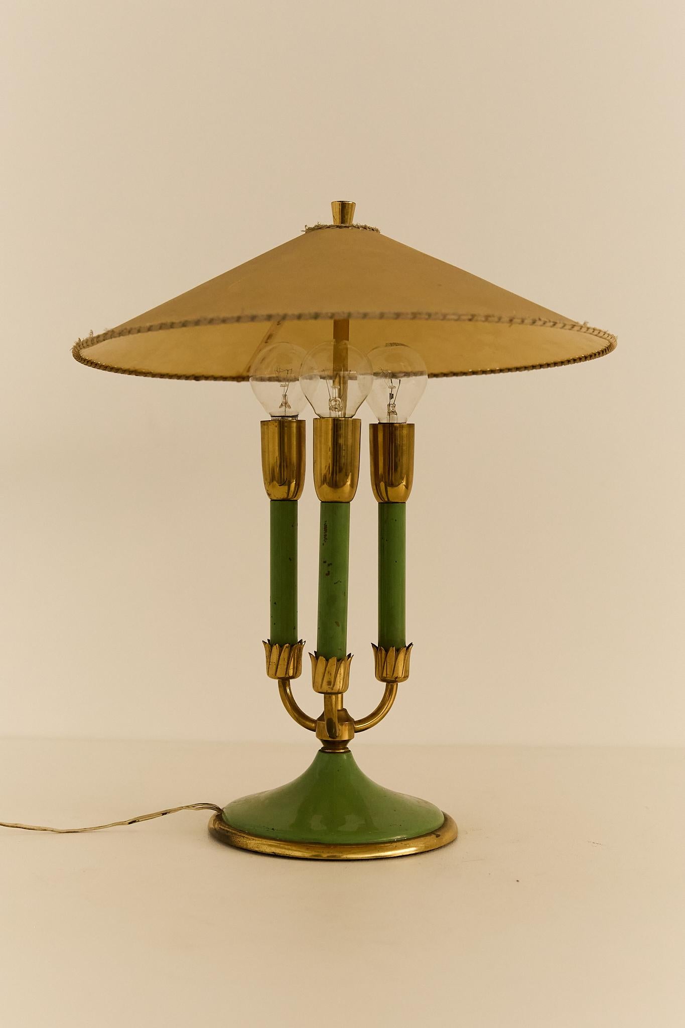 Elegant table lamp featuring a painted metal structure, a fabric lampshade, and refined brass details. 