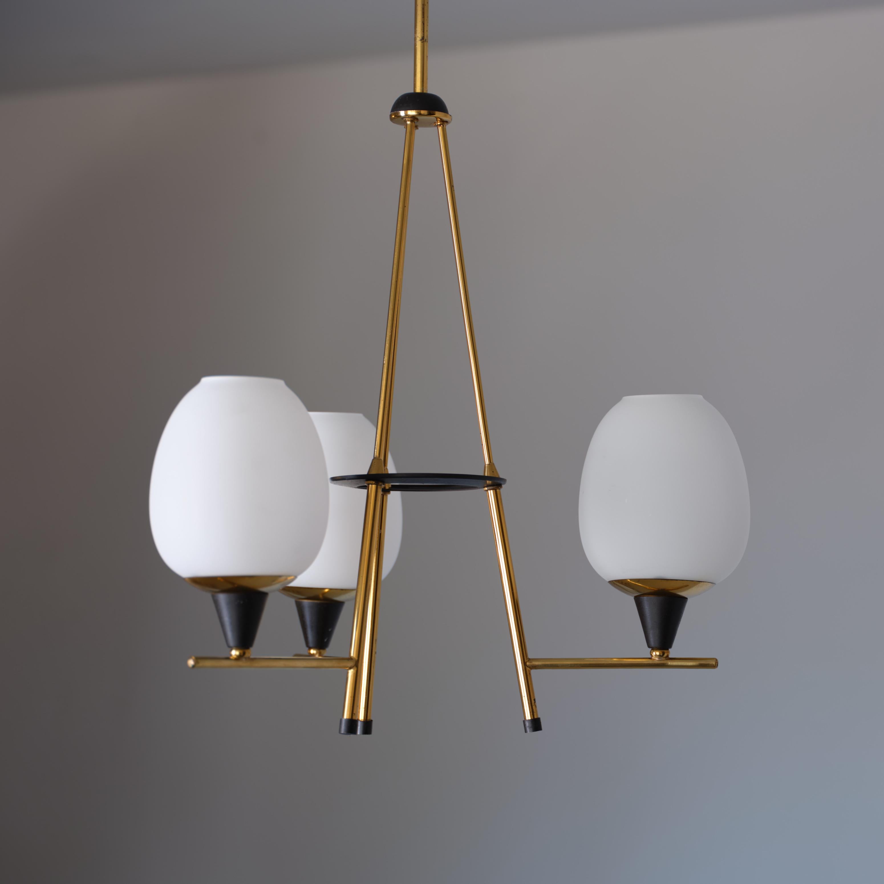 This 1950s chandelier, attributed to the renowned Italian design firm Stilnovo, combines a modern and refined aesthetic typical of mid-century Italian lighting design. The fixture features three light points, each equipped with opaline glass shades,