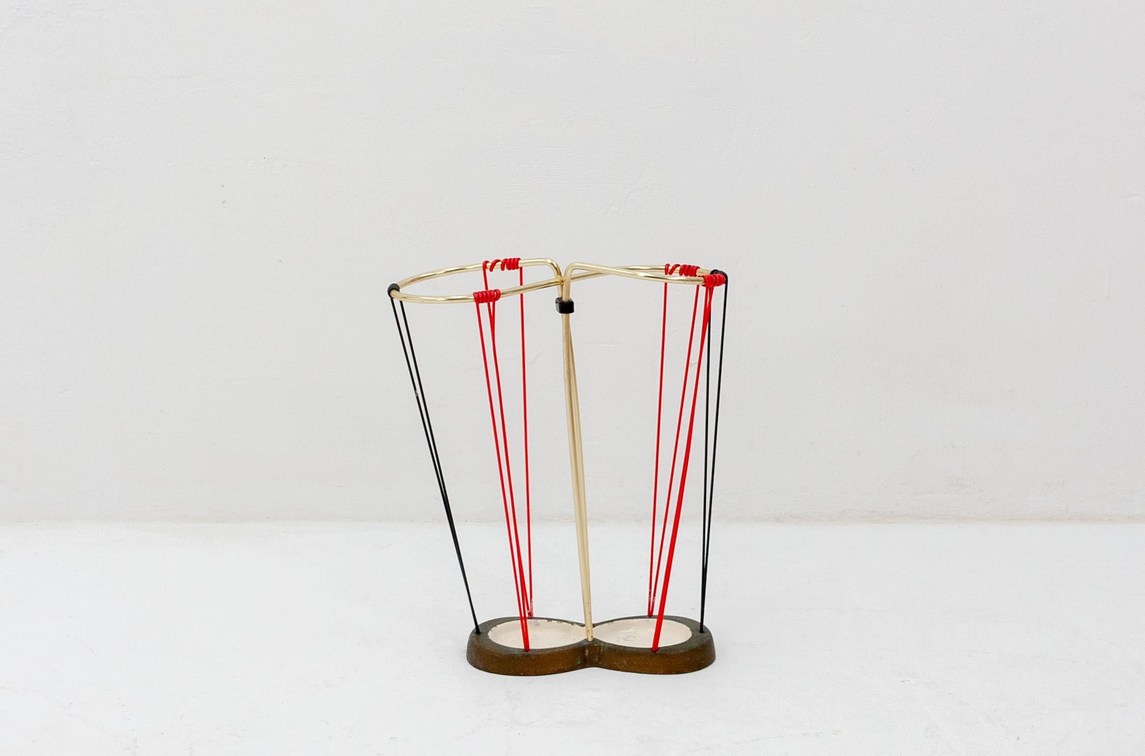 Small vintage Italian umbrella stand featuring a brass rail and red/black retention cords. 
on cast iron base, 1950s.