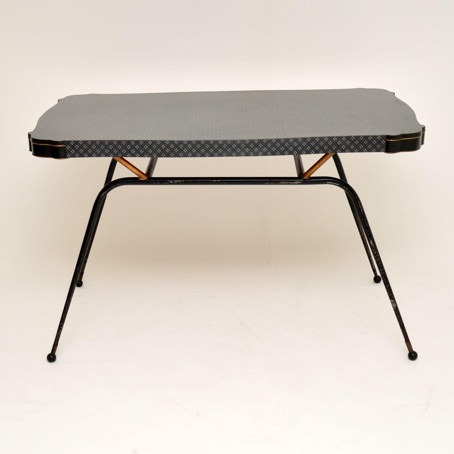 A super stylish and very rare vintage dining table. It was made in Italy, and it dates from the 1950’s.

It has a beautiful shape, patterned Formica top, and amazing ebonised steel base. The legs have brass accents and terminate in lovely