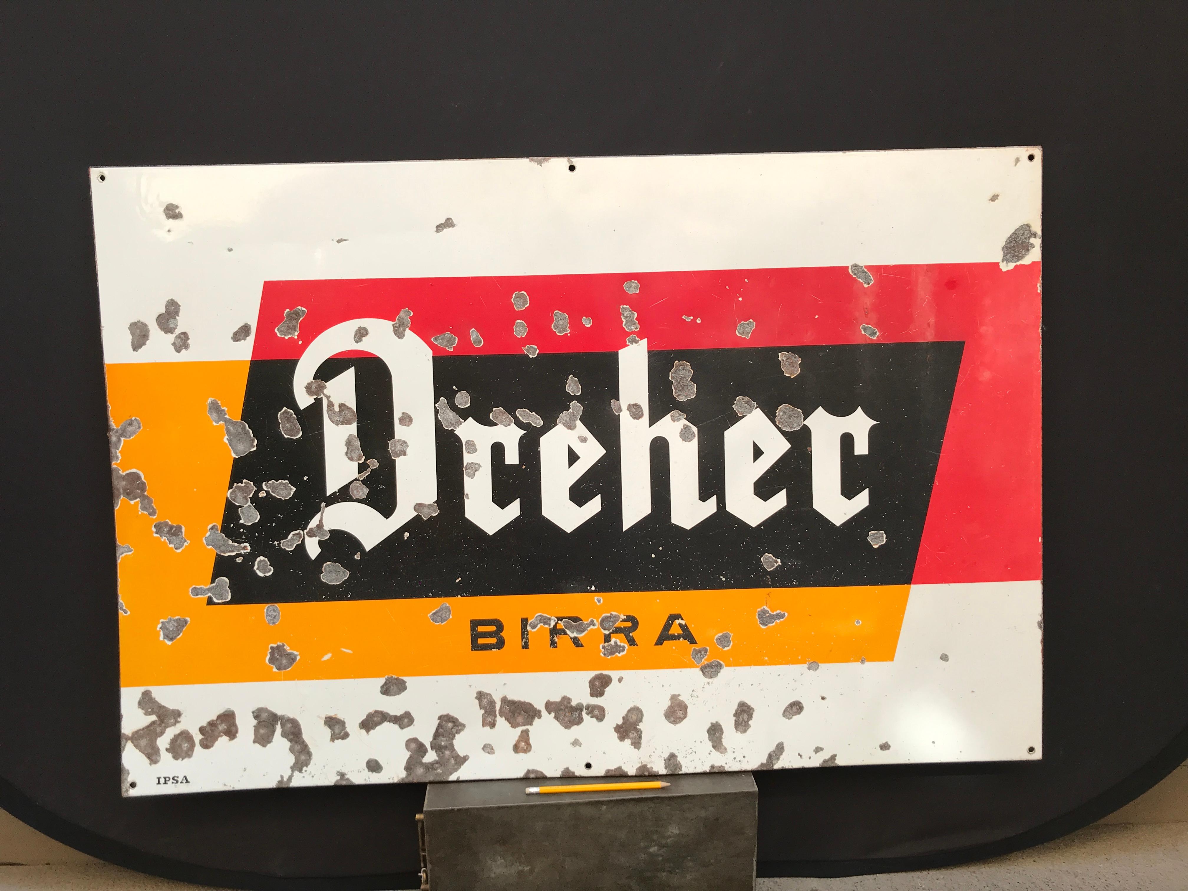 Vintage rectangular metal enamel Dreher Beer advertising sign produced in Italy in the 1950s by IPSA.

The Dreher Birra logo ( Dreher Beer ) in Gothic font lays on a geometric background of orange, red, white and black blocks of colors.

The