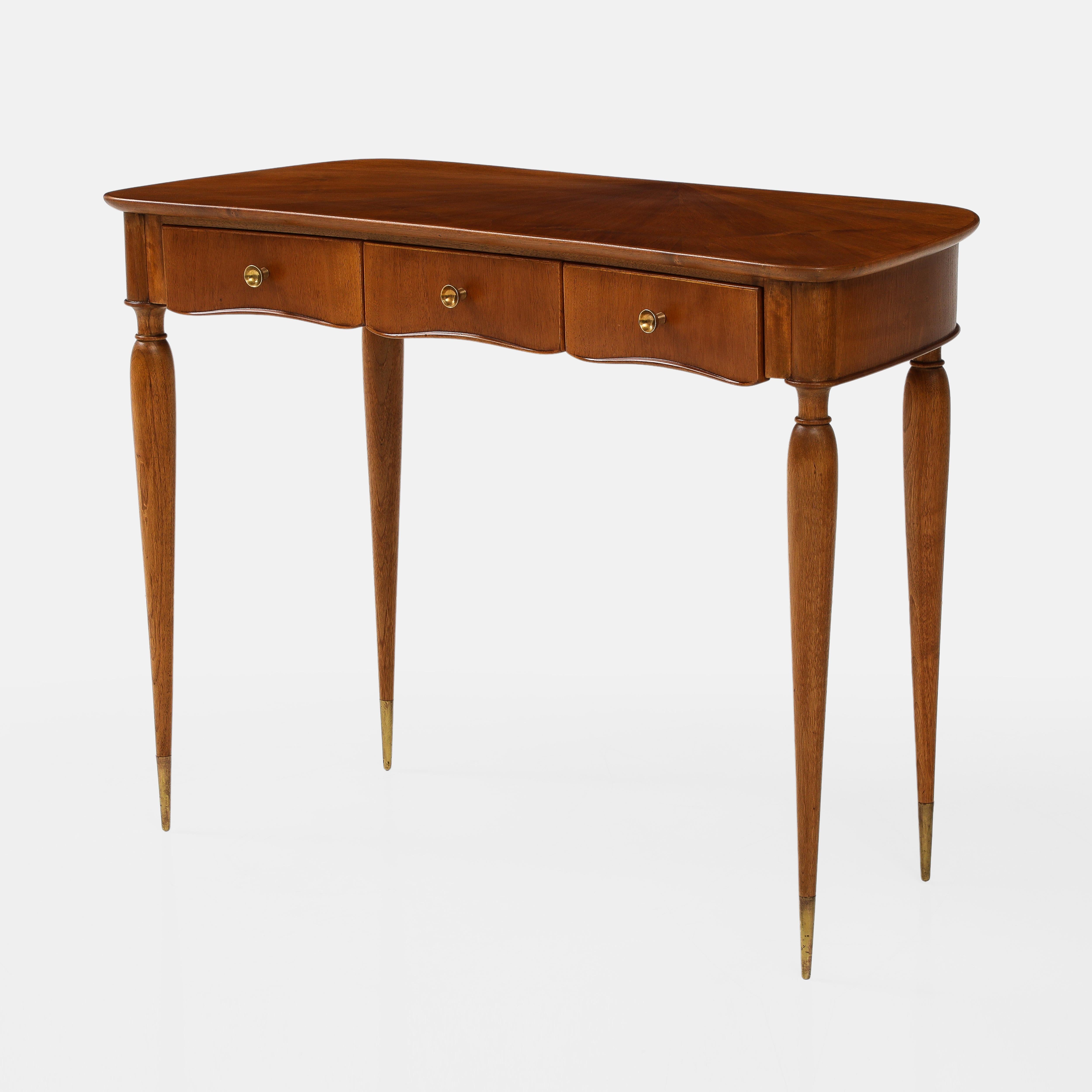 1950s Italian rare walnut wood console or vanity dressing table with slightly curved front edge, three small drawers, and tapering slender pencil legs ending in brass sabots.  This exquisite console or vanity table exhibits fine Italian