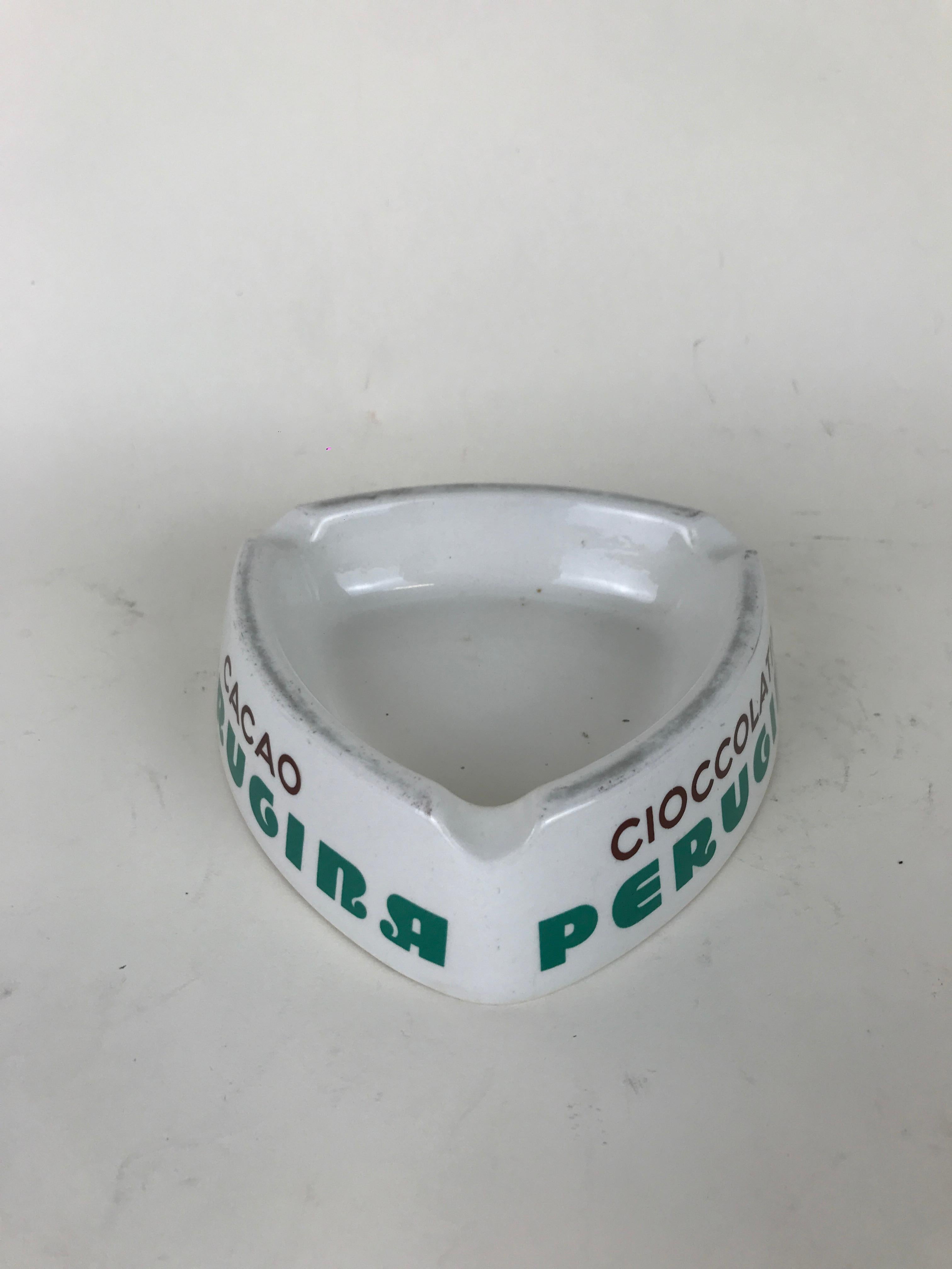 1950s Italian vintage advertising white triangular ashtray with Perugina logo in green on all three sides.
Each side also has a specialty product by the company: 