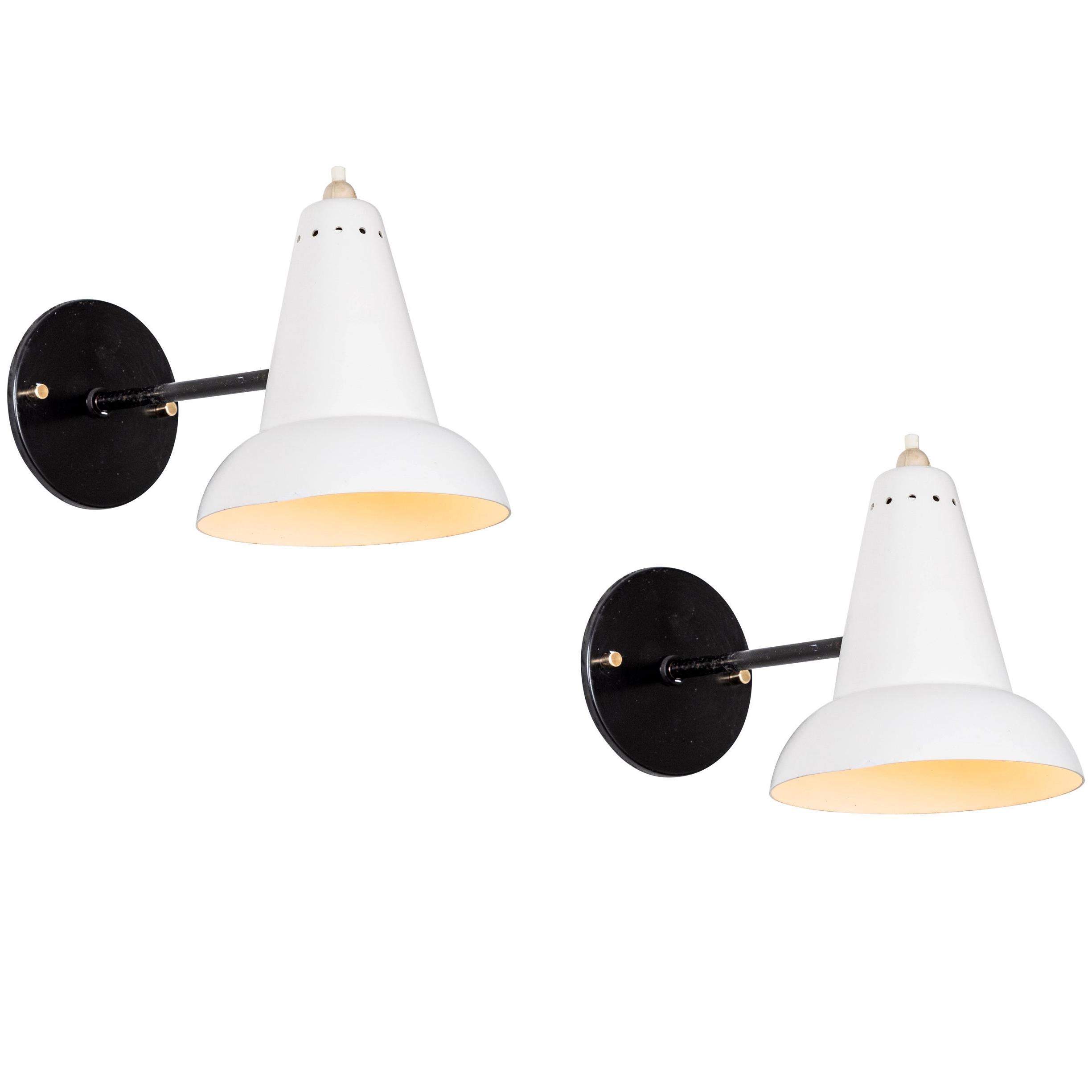 1950s Italian white articulating sconces attributed to Gino Sarfatti. Executed in brass and white painted aluminum. Sconces pivot up or down and left or right on a ball joint. Custom black backplates with brass hardware for hardwiring mounting over