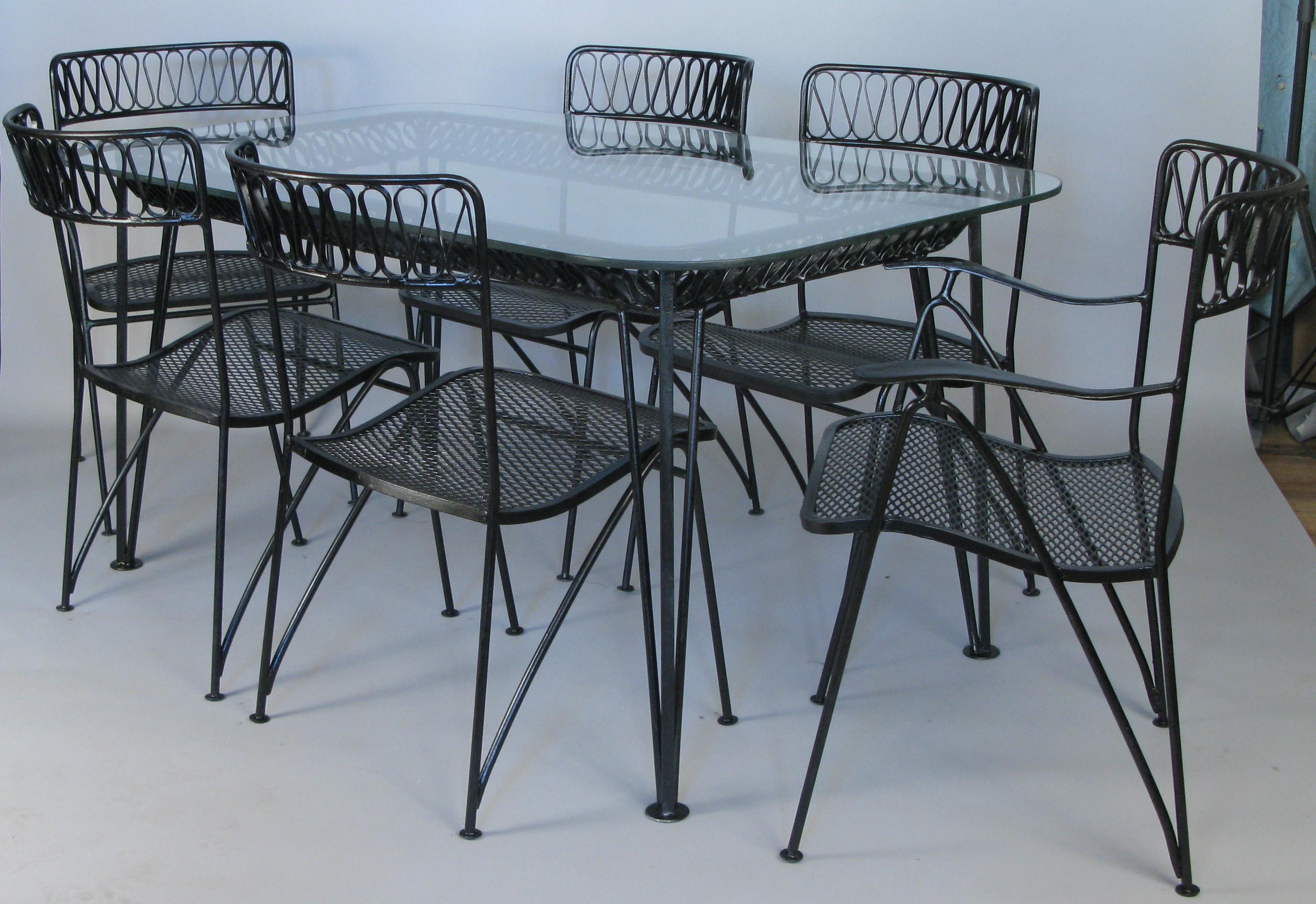 A classic and iconic Salterini dining set from the 1950s. Designed by Maurizio Tempestini, it is one of their most recognizable designs, with heavy and well made wrought iron frames and his dynamic wrought iron ribbon detail in the curved backs of