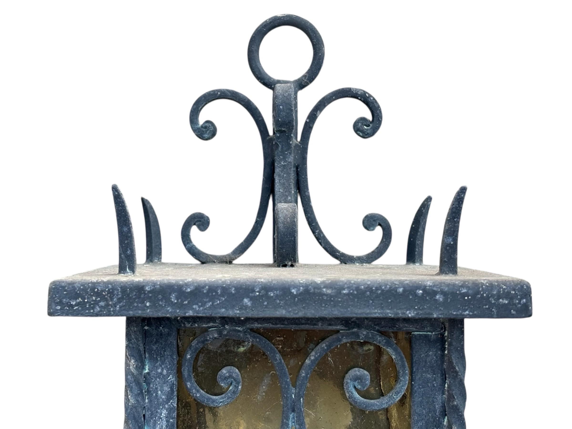 Pair of Italian exterior wall lanterns circa 1950. Amber glass panels are secured with scrolled and twisted wrought iron lanterns. Supported by scrolled wall mounted brackets.