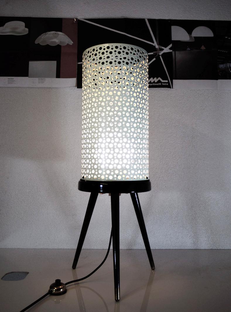Modernist floor lamp with wooden tripod legs and a white, perforated metal shade with an opaline glass globe. Gem from the time. With this light you make a clear statement in your interior design. A real eye-catcher even unlit. Manufactured by