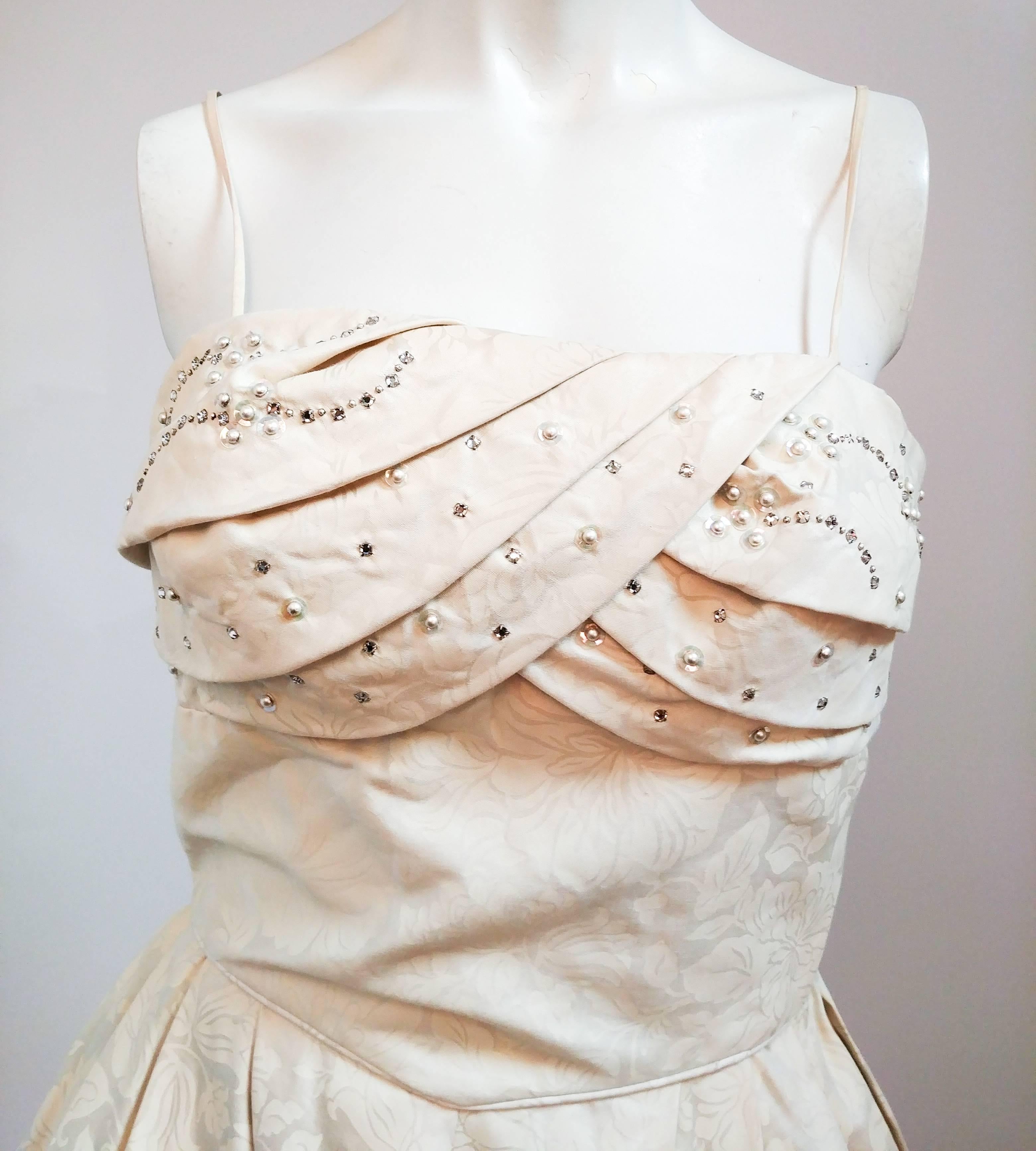 1950er Elfenbeinfarbenes Jacquard-Kleid mit perlenbesetztem Mieder. Drapiertes Brustdetail mit Strasssteinen und Perlen. Taillierte Passform, runder Rock. Das Kleid ist auf dem Bild über einem Unterrock fotografiert.