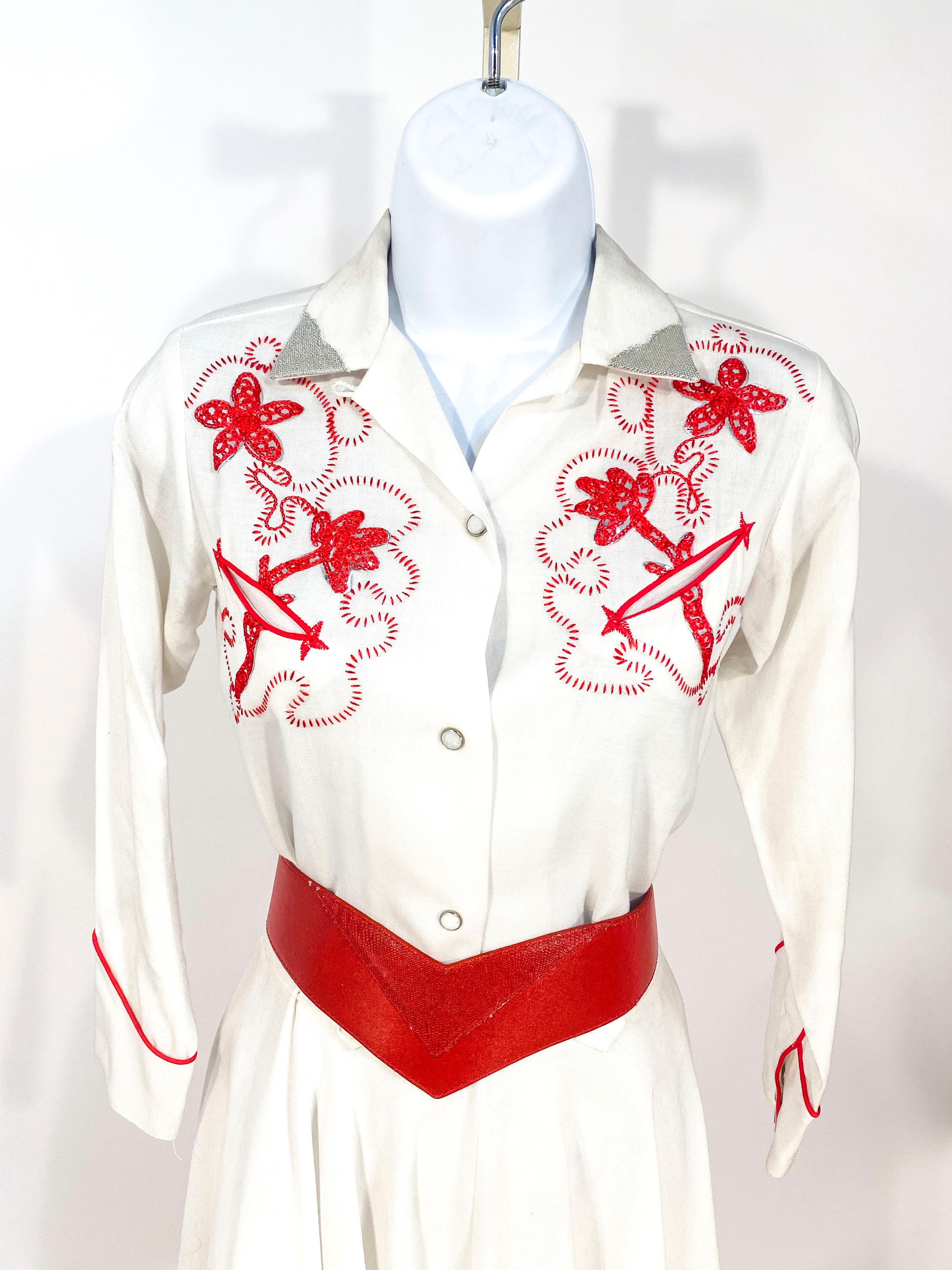 1950s petit J Bar T two-piece cowgirl set (shirt and matching skirt) in white with cactus flower embroidery in a coral red tone. The embroidery has touches of lurex foil. The front of the shirt and the cuffs have pearl-snap buttons and the skirt has