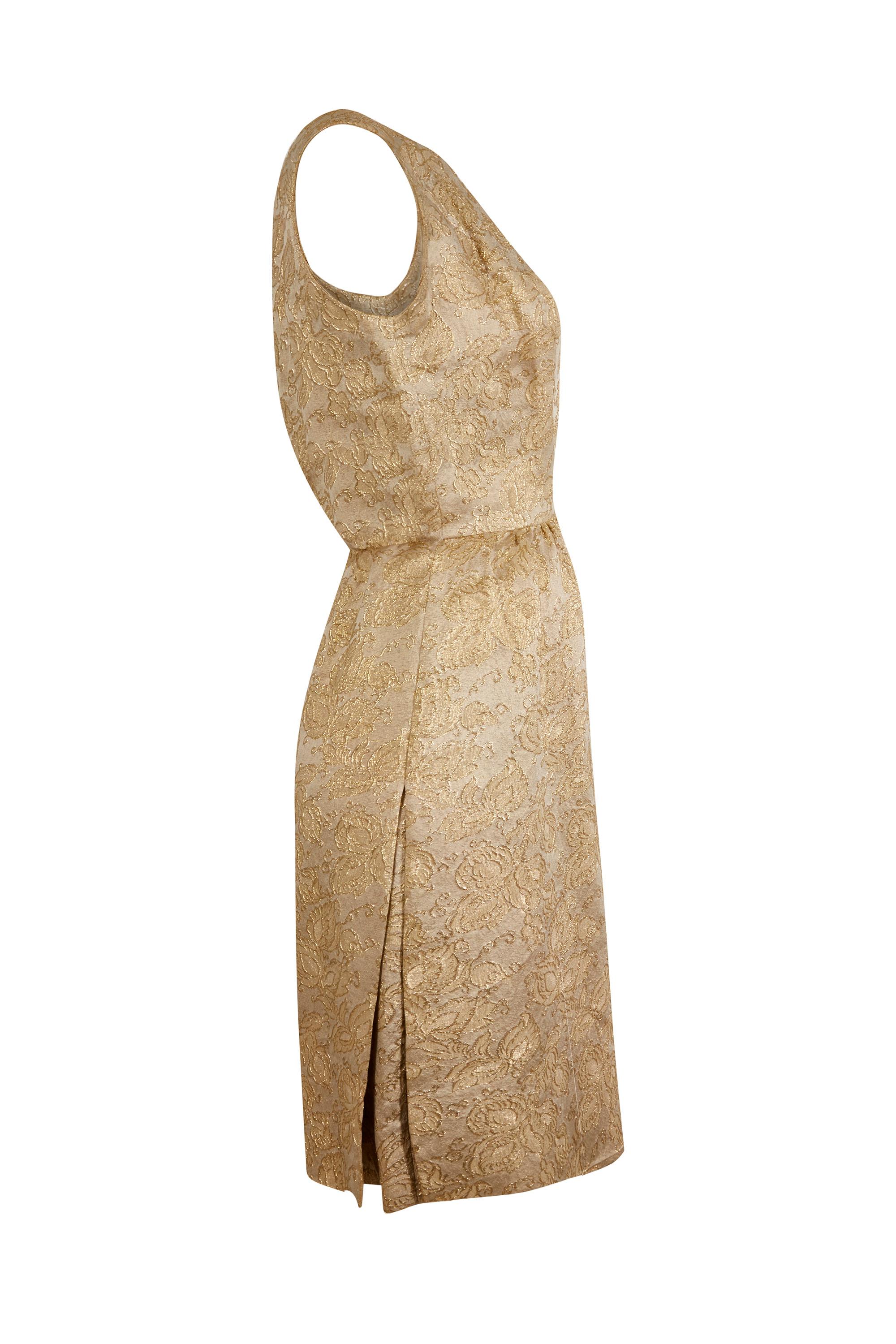 This dazzling 1950s gold brocade cocktail dress is demi-couture from Parisian designer Jacques Heim and has both simplicity and glamour with some beautiful construction details. The gold floral brocade fabric of the dress glitters pleasingly where