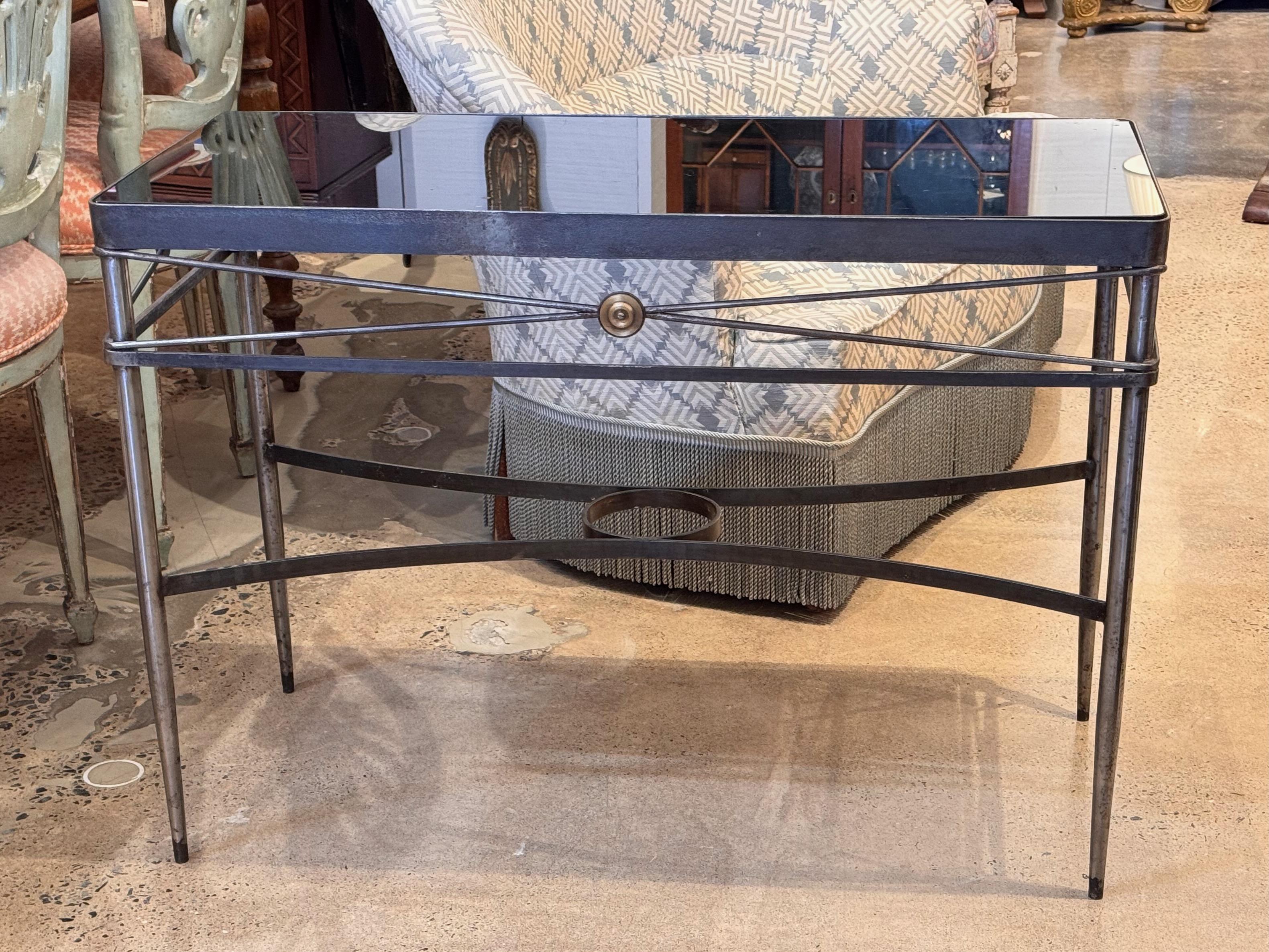 Sleek metal console in the style of Maison Jansen, featuring a black glass top and classic cross-stretcher design with central rosette medallion. The tapered legs and lower curved stretcher add elegance and lightness, making this an ideal hallway or