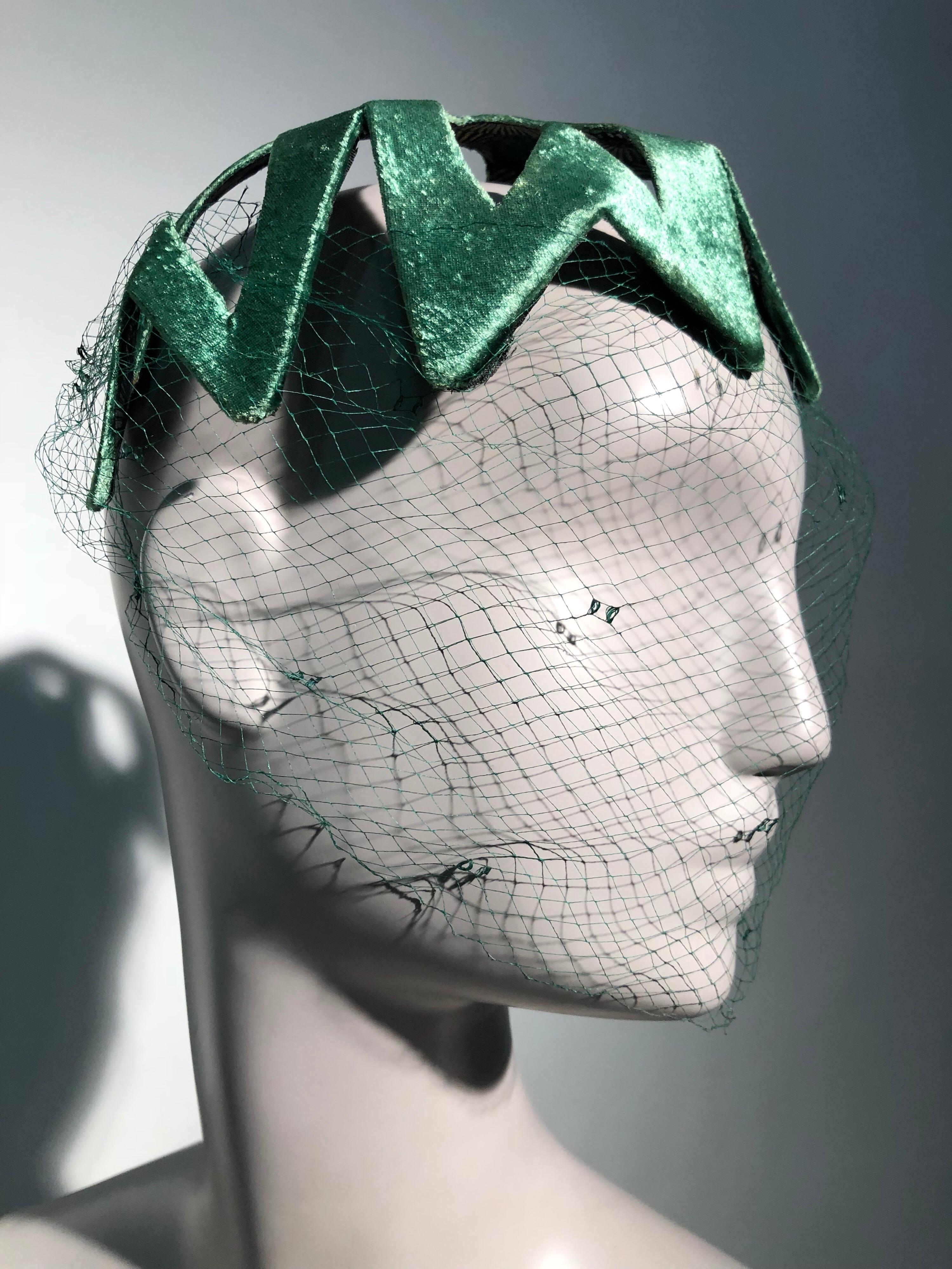 A fabulous 1950s statement hat, most likely from Japan. This emerald green satin stunner is stiffened and molded to fit the front of the head and is lined with a traditional Japanese chrysanthemum pattern. You'll love this bold graphic cut-out