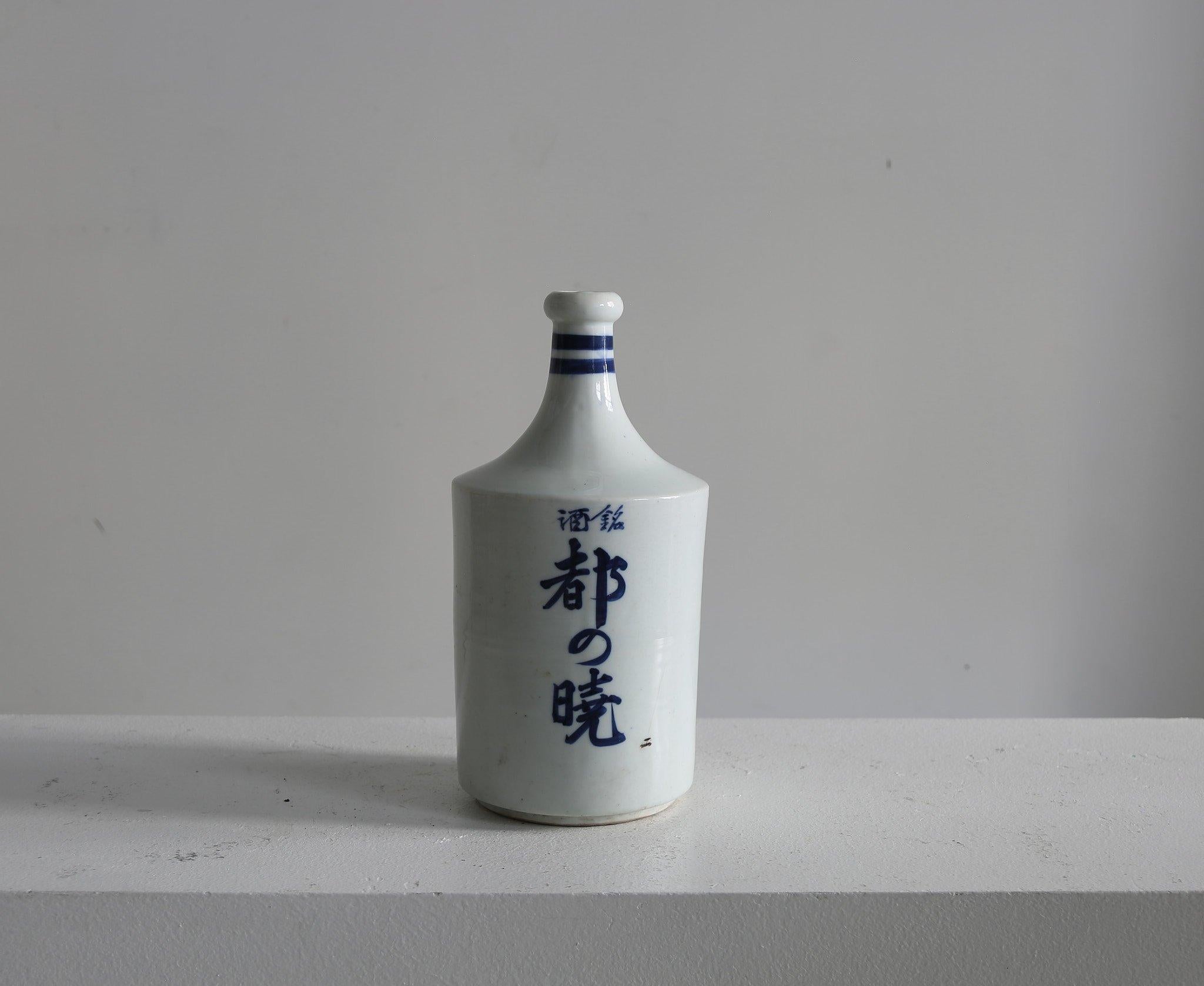 Audace bottiglia di sakè in ceramica. 

Decorata a mano con il nome della distilleria locale e quello della famiglia proprietaria, che riutilizzava la bottiglia ogni volta che era necessaria per una celebrazione.

Dalla regione di Hokkaido in
