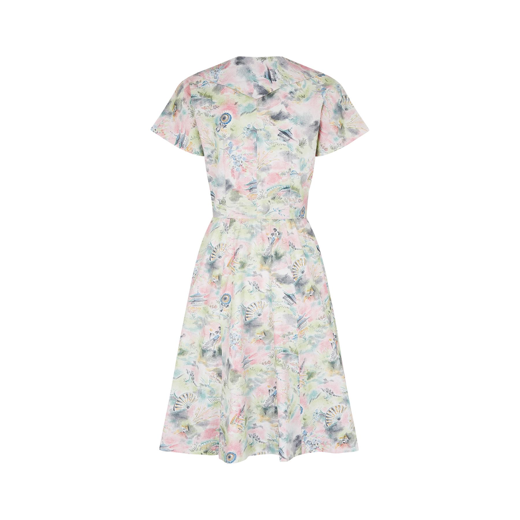 This is an original 1950s or early 1960s cotton dress with a very desirable novelty painterly scenic print showcasing a Japanese couple in traditional dress; Japanese fans and umbrellas; flora and fauna; and pagodas. The colour palette is lovely