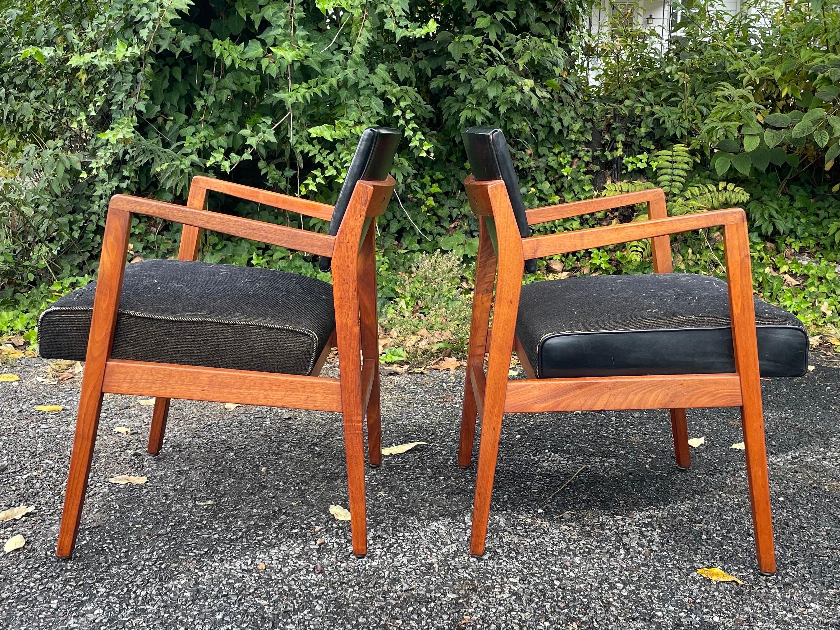 A pair of upholstered chairs with walnut frames with sleek, Scandinavian lines in the manner of Jens Risom. Made by The Taylor Chair Co of Ohio circa 1950s. Leather back rests and fabric seats. Extremely comfortable and very sturdy. Gorgeous wood