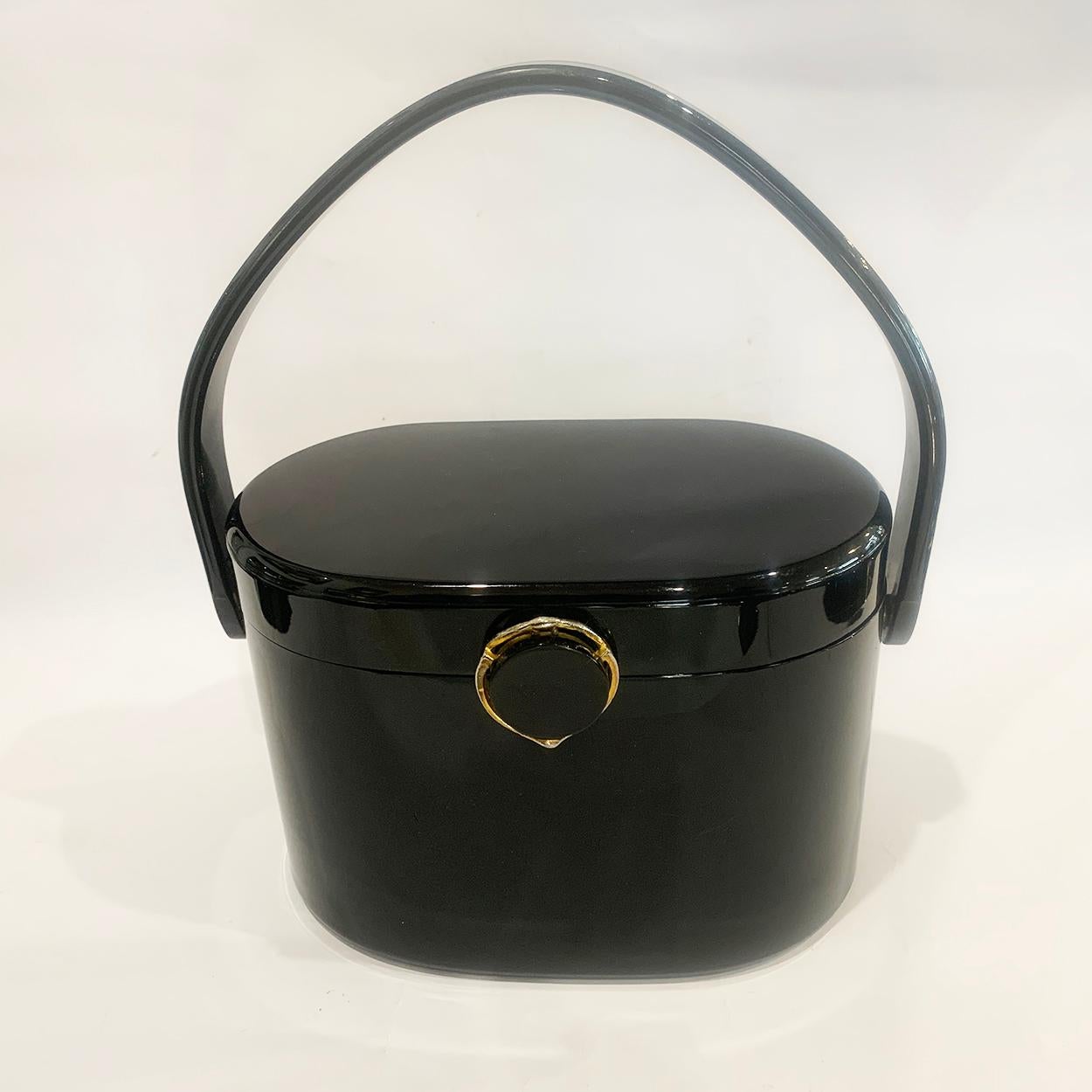 Mid Century solid, jet Black Lucite Handbag in a double “D” Shaped ends and triangular swivel handle. Fitted with decorative, gilt edge, “snap” clasp in perfect working condition. Internal oval Mirror, with by ”Wilardy” engraved to inner Piano