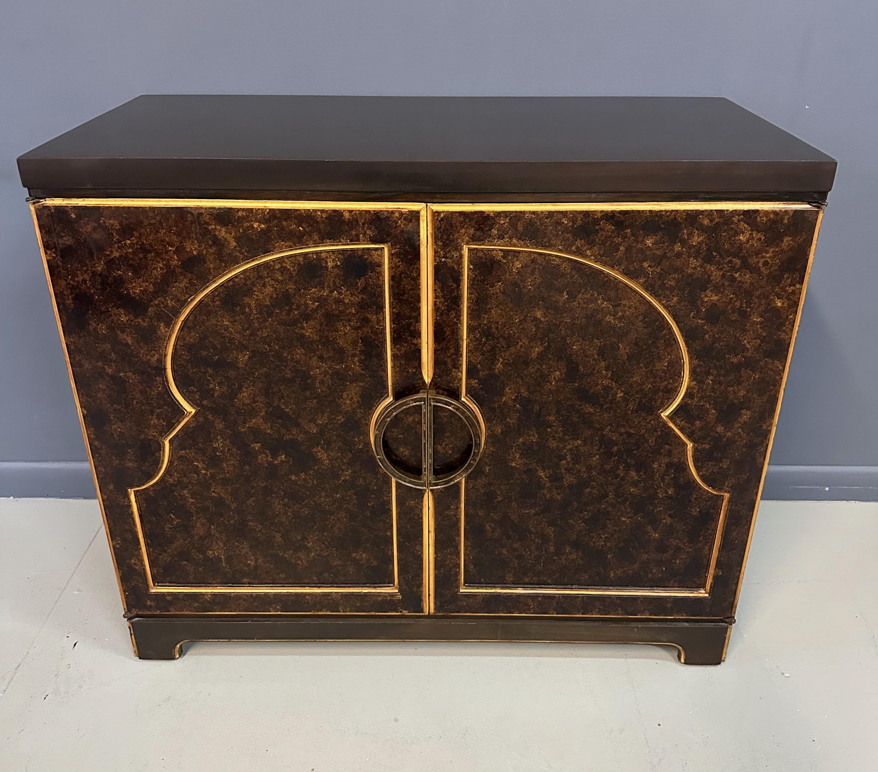 This 1970s John Widdicomb Commode features a faux tortoise shell finish, providing a unique and sophisticated touch to any mid-century styled room. With its timeless design, this commode is a perfect addition to elevate your interior decor. Expertly