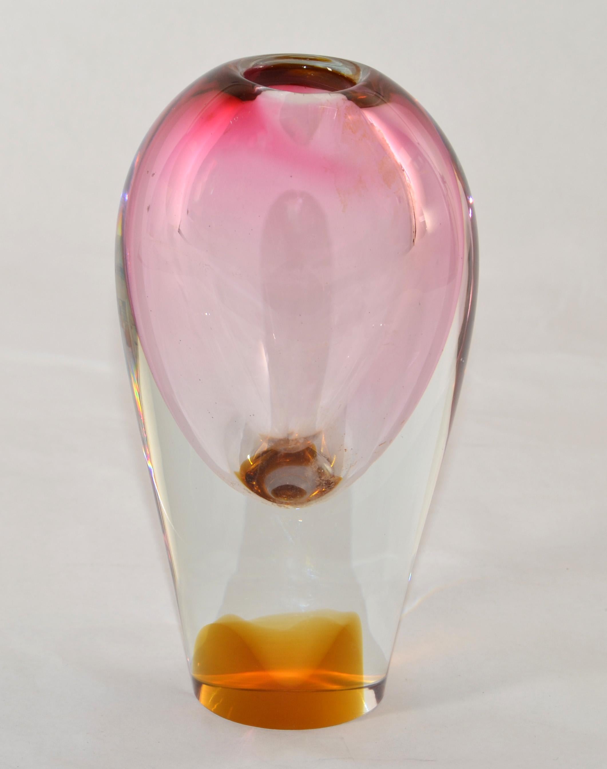 Questo bellissimo vaso massiccio soffiato a mano è caratterizzato da un cristallo trasparente che racchiude sottofondi in rosa ombreggiato e ambra calda. Il vaso ha una base alta e pesante e una cavità sferica con un'apertura stretta.
Non c'è Label,