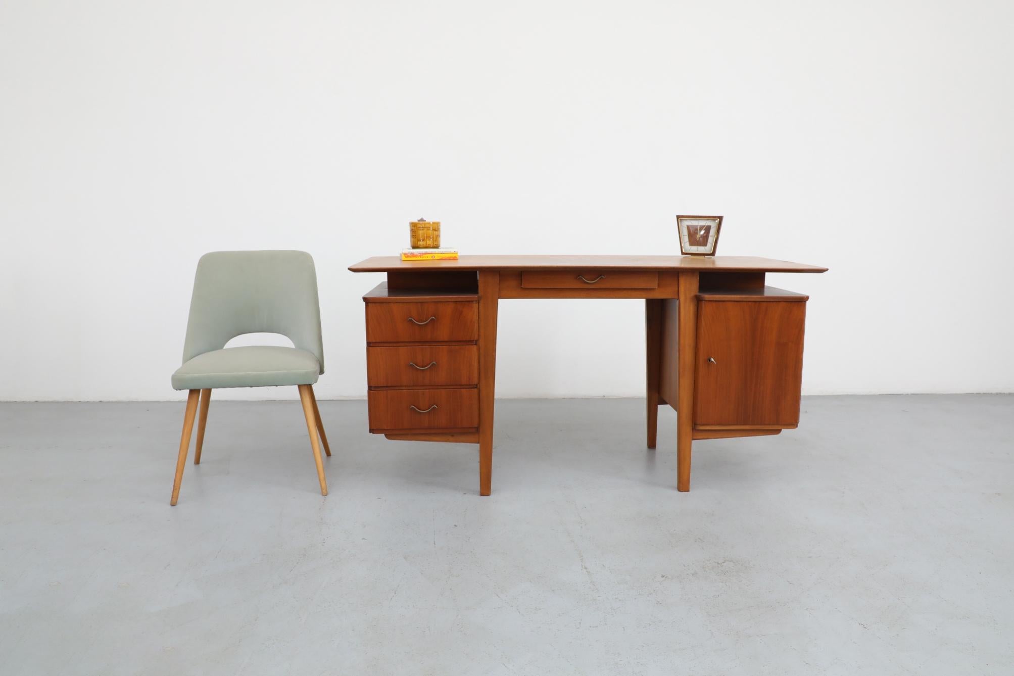 Dutch Mid-Century, 1950's, Kai Kristiansen style pecan writing desk with floating top. Lightly refinished teak frame. Desk has three drawers on one side with a cabinet on the other. Top bows downward at sides and corners, but still relatively flat