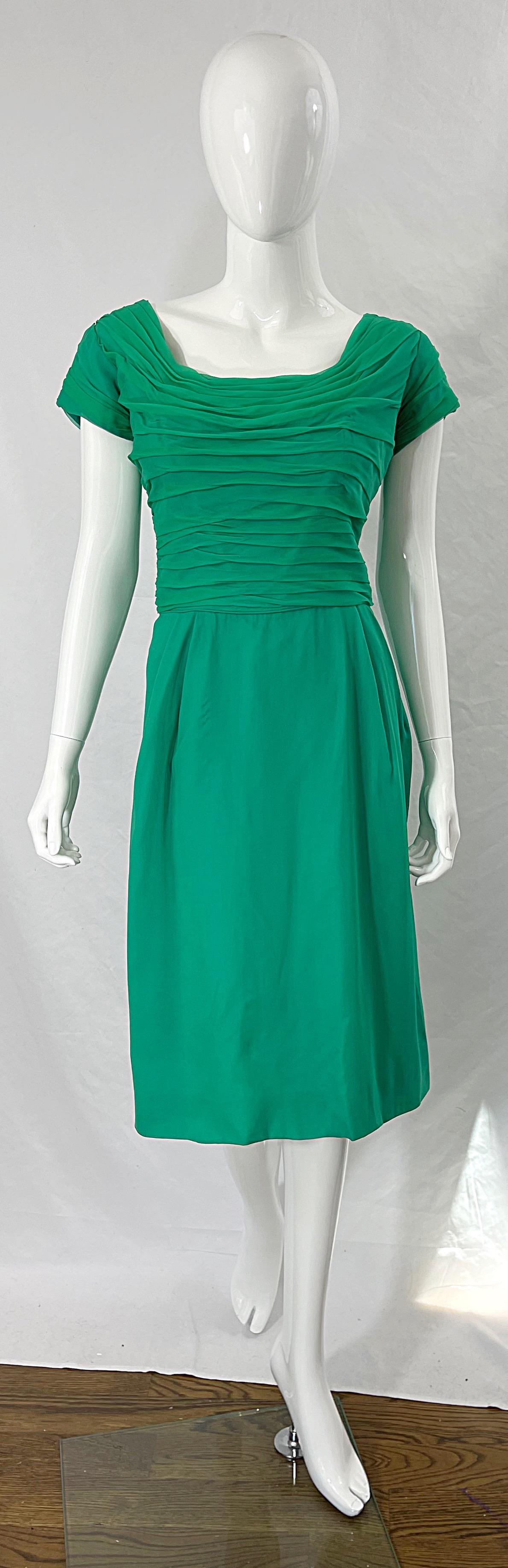 Chic 1950s kelly green Demi couture silk chiffon short sleeve cocktail dress ! Features an intricate tailored pleated bodice with a straight skirt. Hidden metal zipper down the back with hook-and-eye closure. I love the slight train on the back.