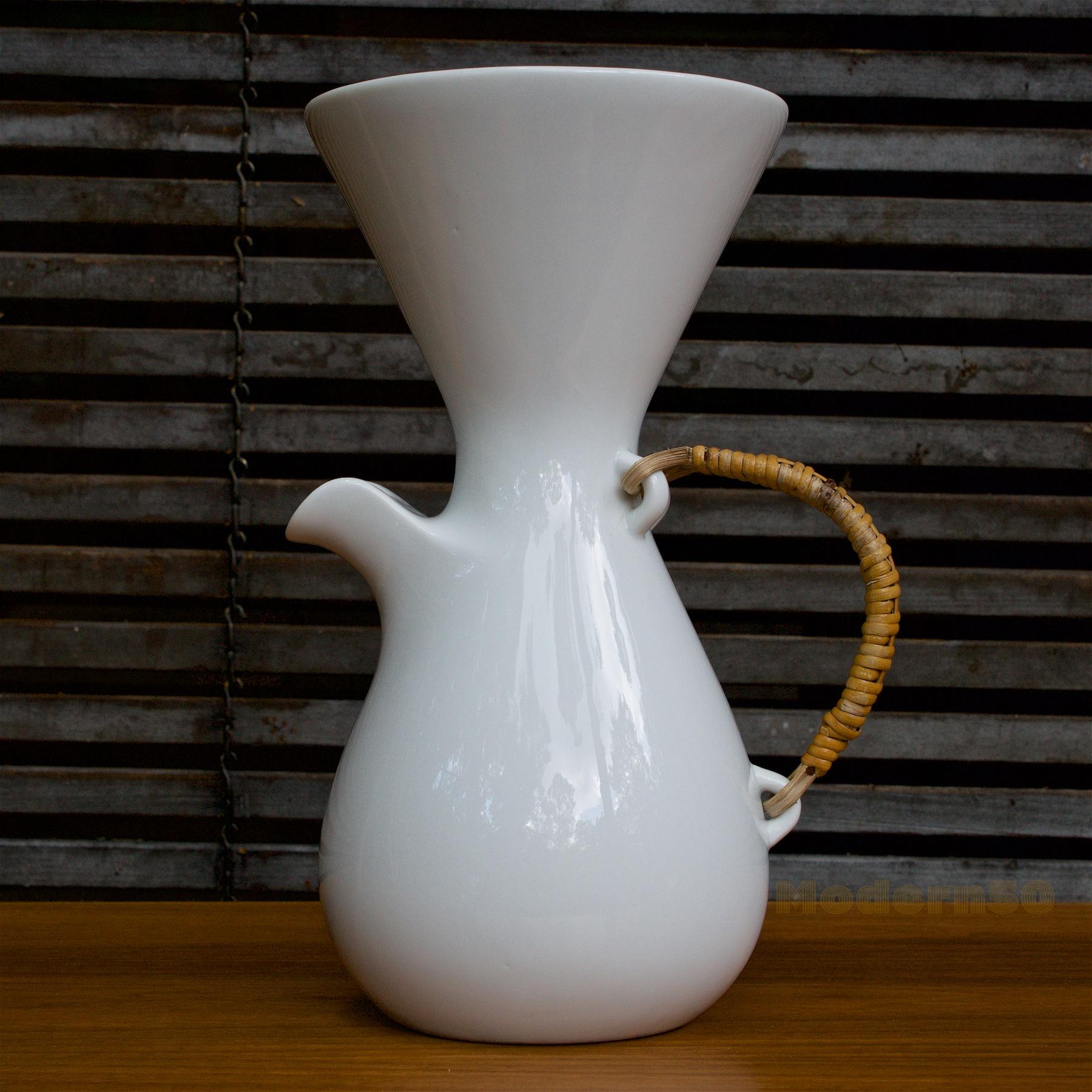 Wonderful white porcelain hourglass pitcher, original rattan handle is in good usable condition, porcelain has no chips, and no cracks. Top rim diameter is 5 3/4.