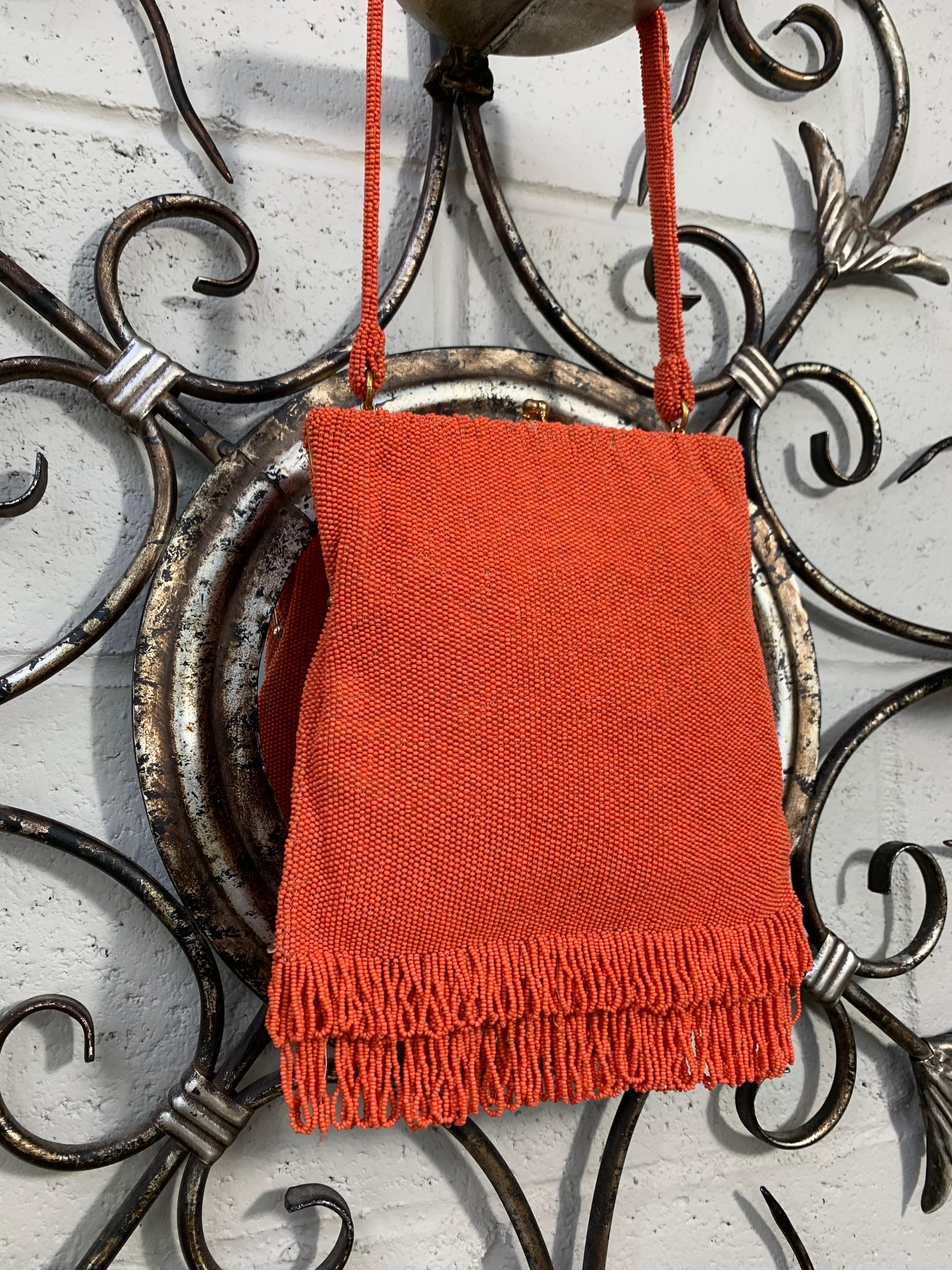 1950s Koret coral color seed beaded handbag with beaded handle, seed bead looped fringe bottom and cobalt blue silk satin lining. Excellent condition. Medium sized, will accommodate a large cell phone. 