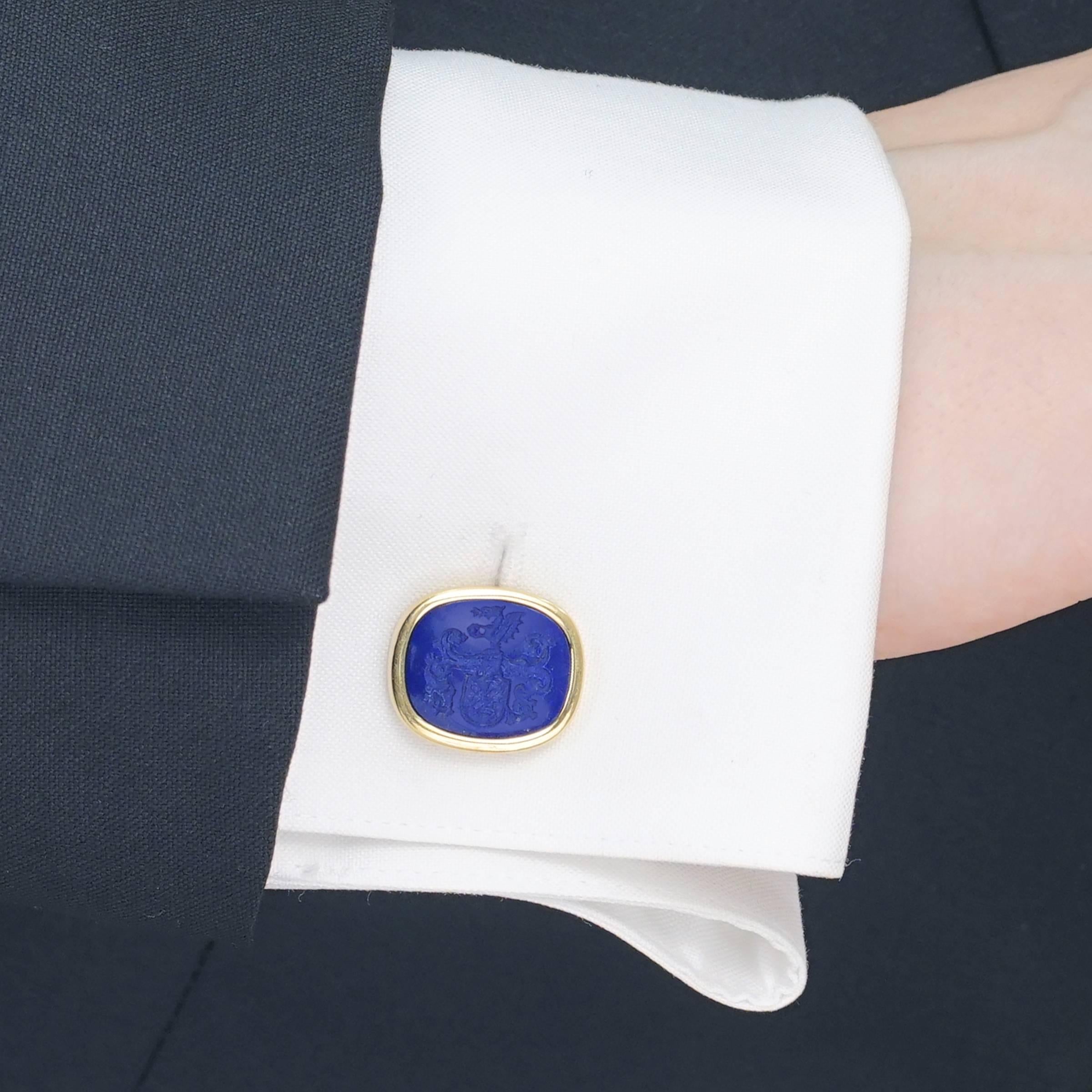 Circa 1950s, 18k, Swiss.  These sublime lapis lazuli cufflinks are perfect signature accessories to add to a well-edited fashion collection. Finely carved intaglio coats of arms, superb gold-flecked lapis and 18k gold frames create an elegant visual