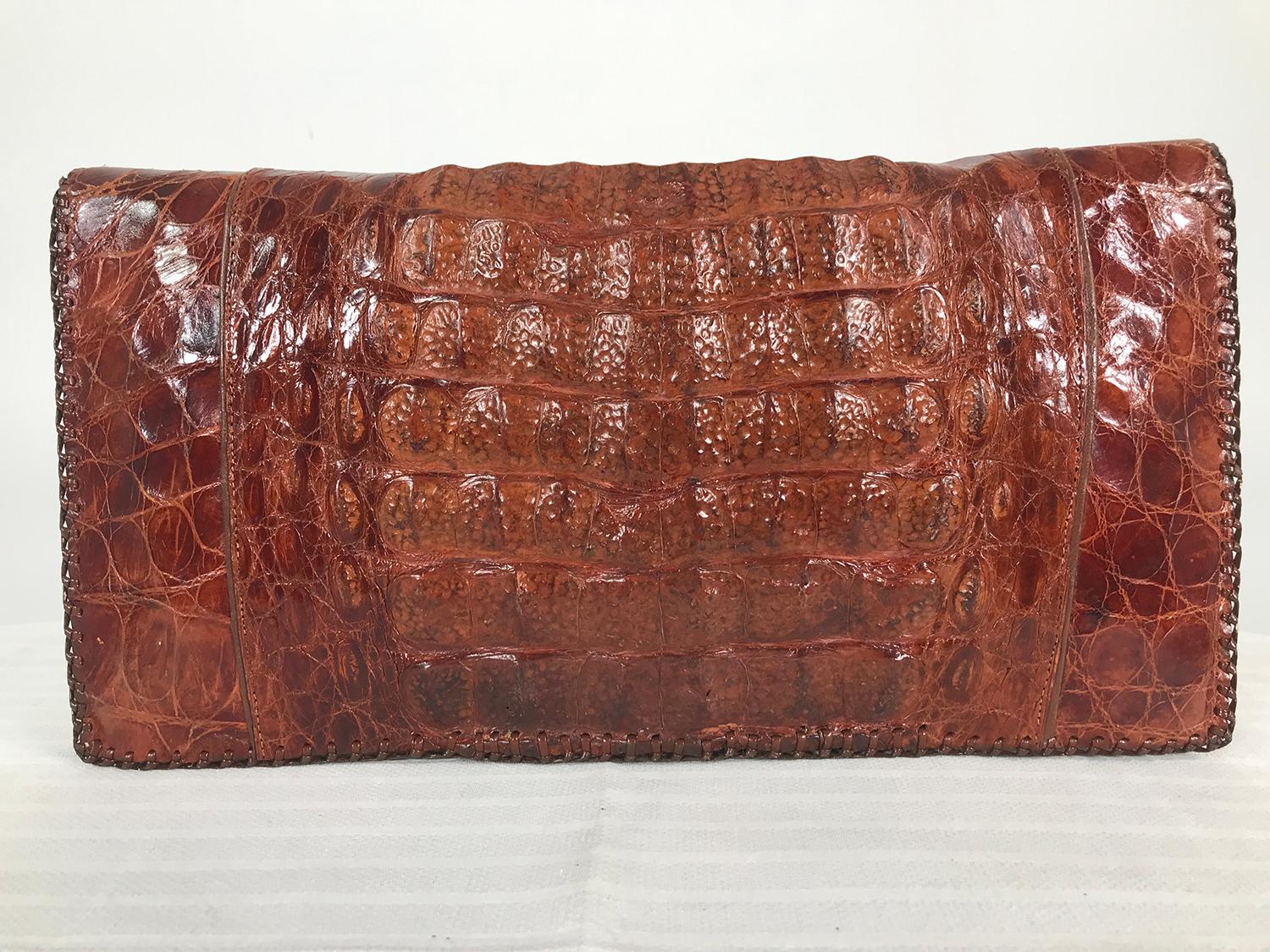 1950s large alligator clutch handbag. Unusually large alligator clutch handbag from the 1950s, in amber colour skin. The bag is long and folds in half, it is finished at the edges in a whip stitch, the interior is chocolate brown leather, there is a
