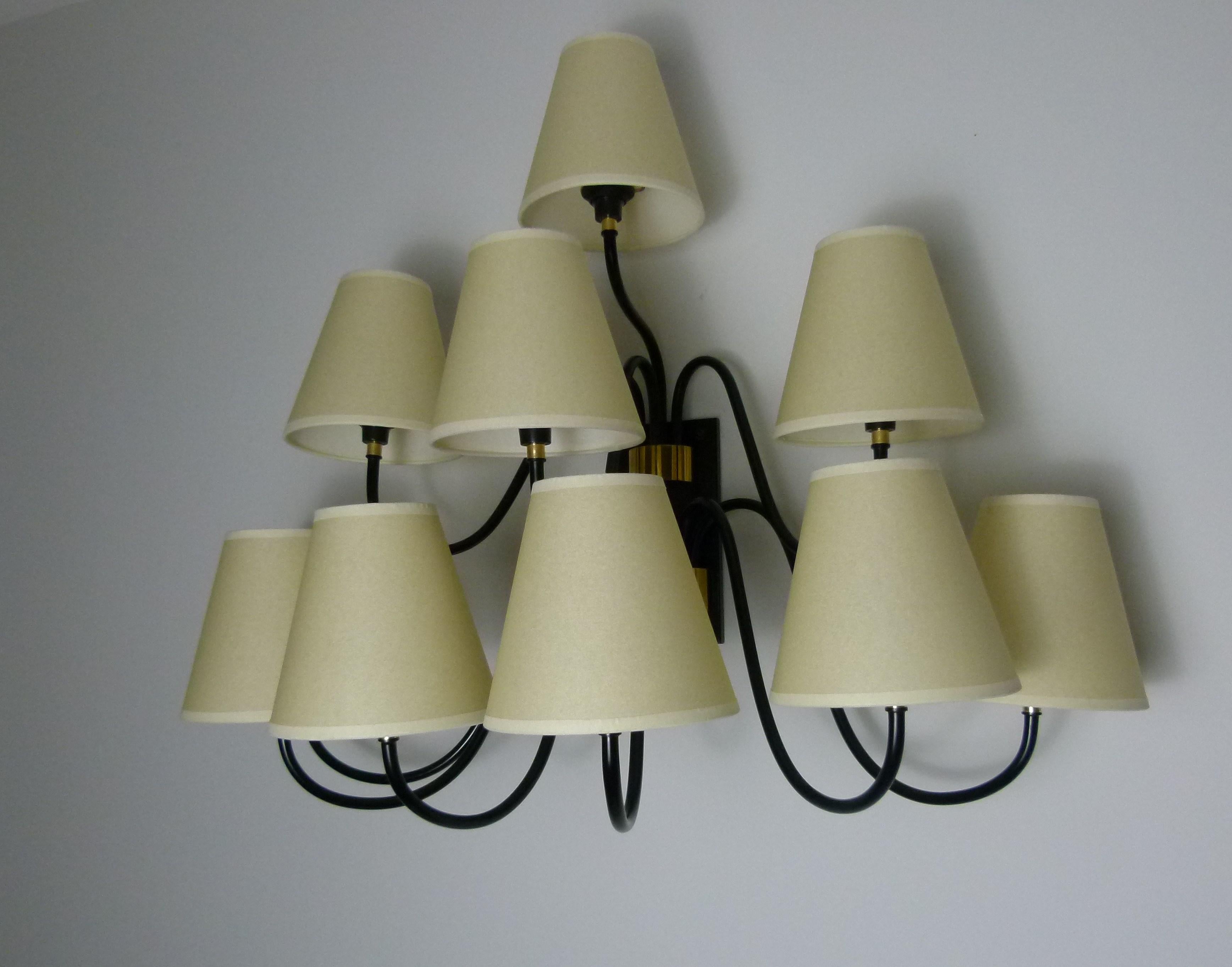 Large wall sconce with 10 arms of light consisting of a rectangular base in black lacquered metal.
A set of four black lacquered metal sconces completed by conical lampshades are fixed on a brass support, and a second set consisting of 6 light beams