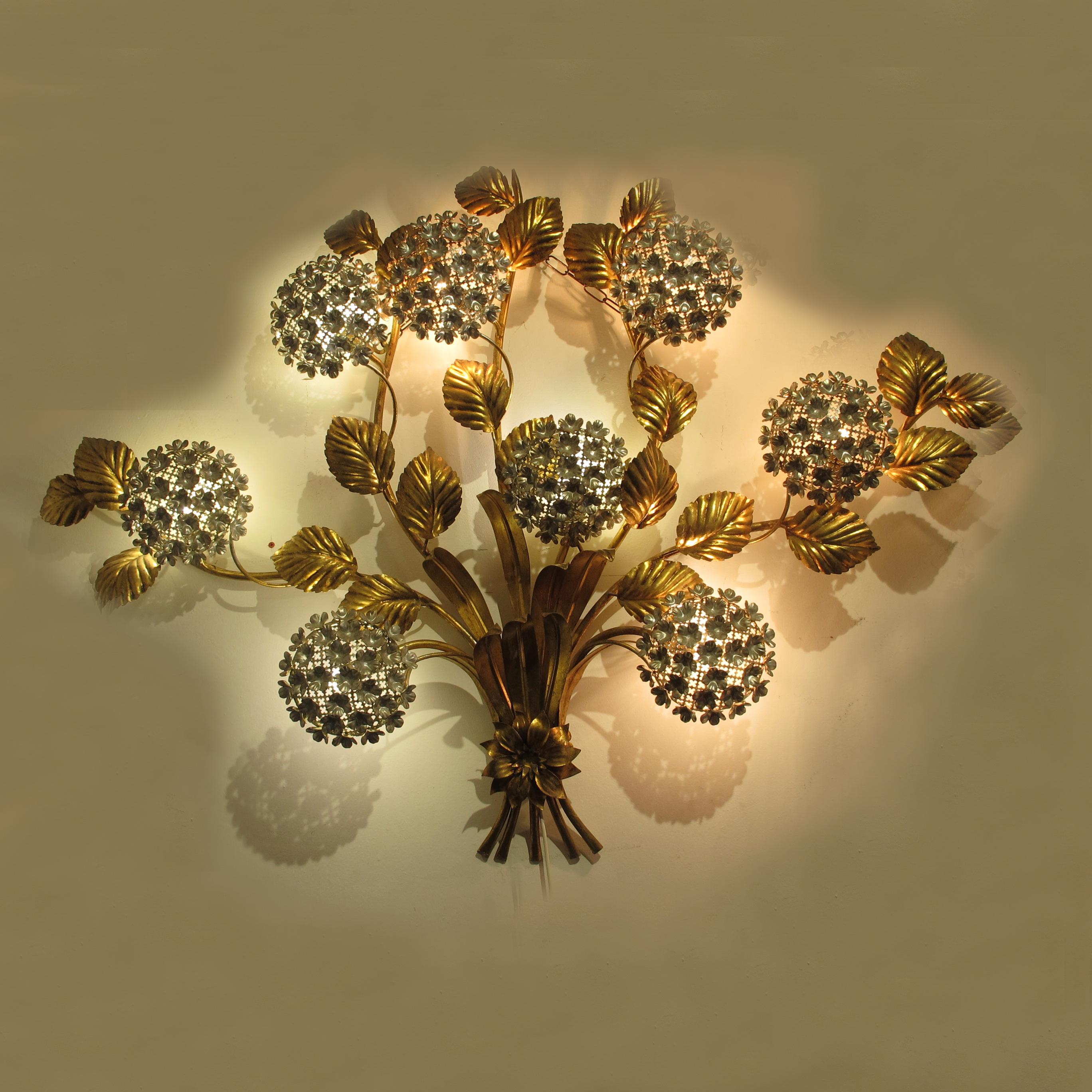 This striking piece is a testament to Hans Kogl's timeless artistry and showcases the perfect fusion of form and function. When illuminated, the Toleware Hydrangeas Wall Light emanates a warm and inviting ambience, casting a soft, diffused glow that