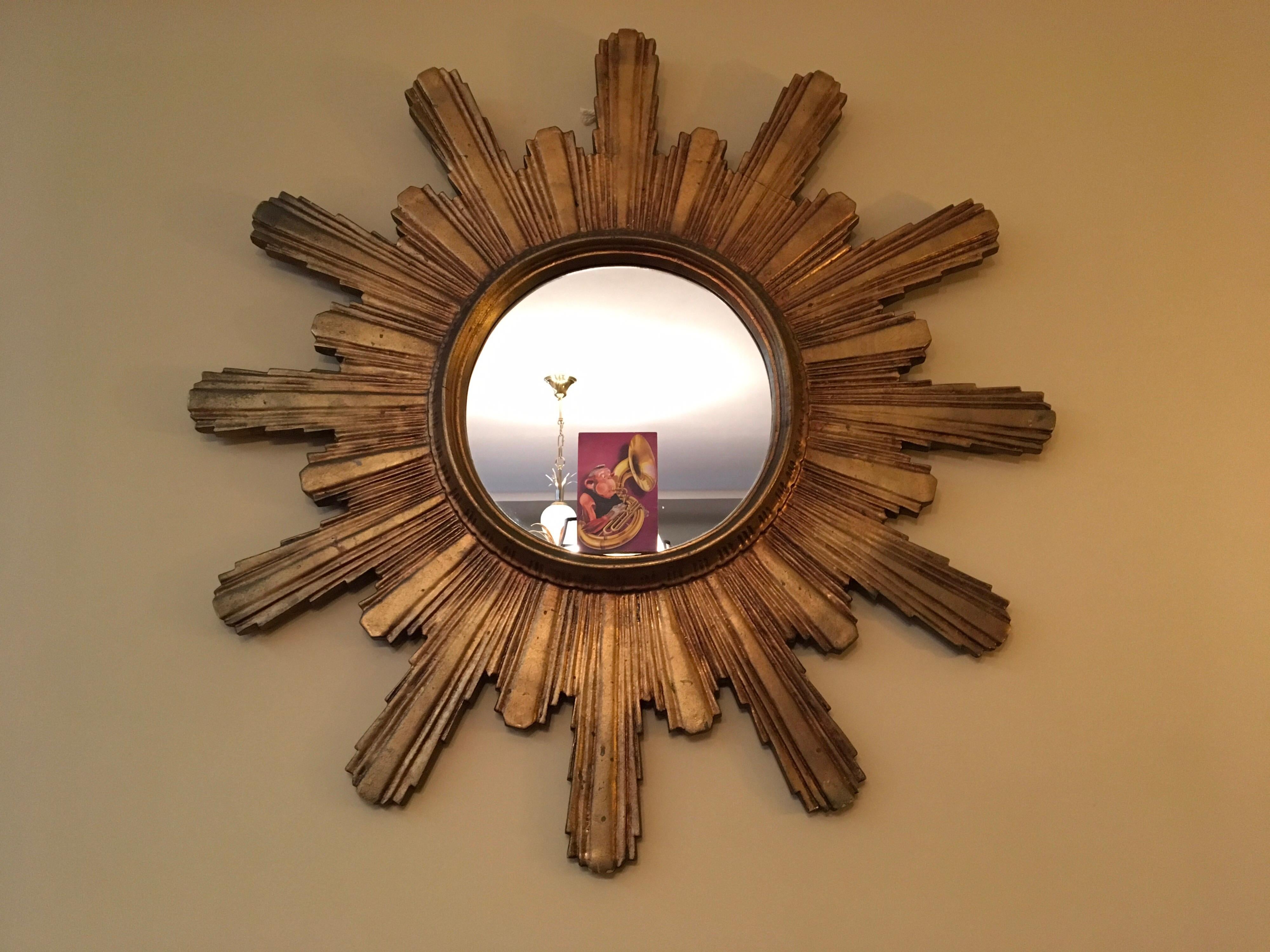 Spektakulärer großer vergoldeter Holzspiegel mit Sonnenschliff oder Starbust-Spiegel. 
Dieser Spiegel aus den 1950er Jahren hat einen vergoldeten, geschnitzten Holzrahmen.
Der Gesamtdurchmesser dieses großen hölzernen Sonnenschliff-Spiegels beträgt