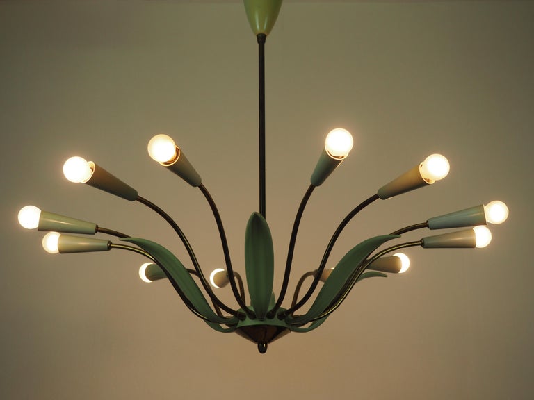 A large twelve-light midcentury Stilnovo style brass Sputnik chandelier.
This beautiful high quality chandelier is made of green enameled and patinated brass and plastic caps for twelve e14 standard screw bulbs.




  