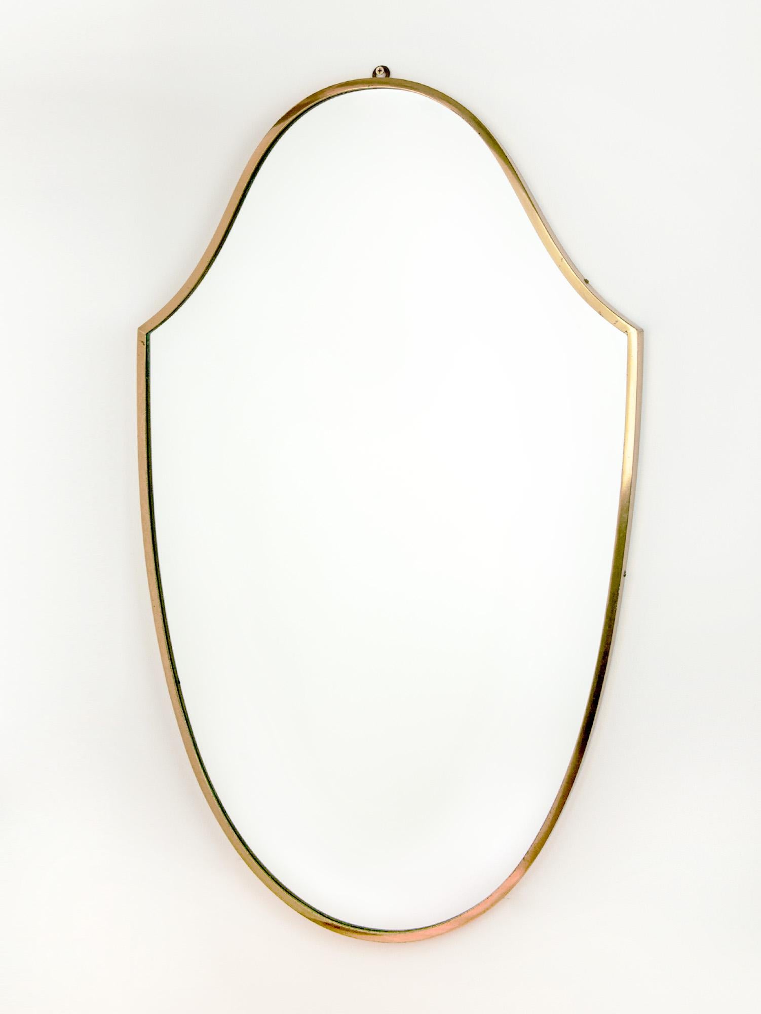 Large vintage Italian brass mirror with a brass surround. The classic shield shape epitomizes Italian modernist design. The brass frame holds the glass and wooden backing with a hook above the mirror. Made circa the 1950s.

Great vintage condition