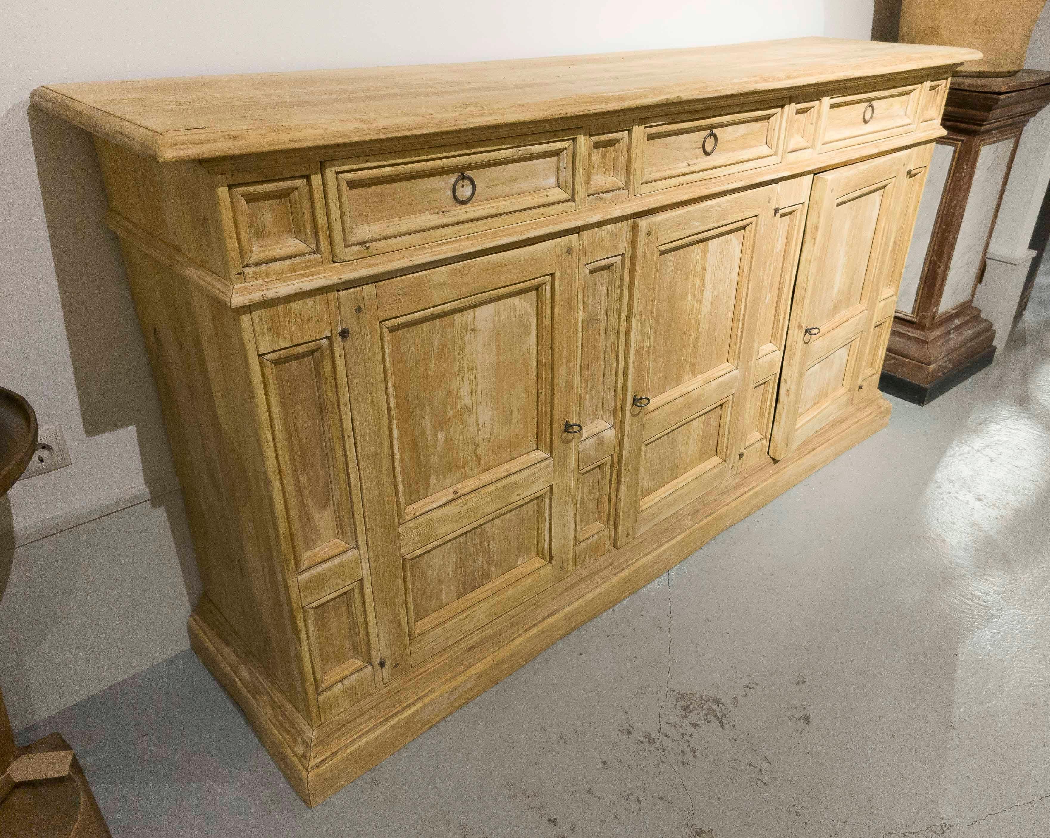 Un'incredibile credenza di grandi dimensioni realizzata in legno massiccio con un'attraente finitura anticata che ne evidenzia il carattere caldo e rustico. Presenta un layout estremamente funzionale con diversi cassetti superiori e spaziosi
