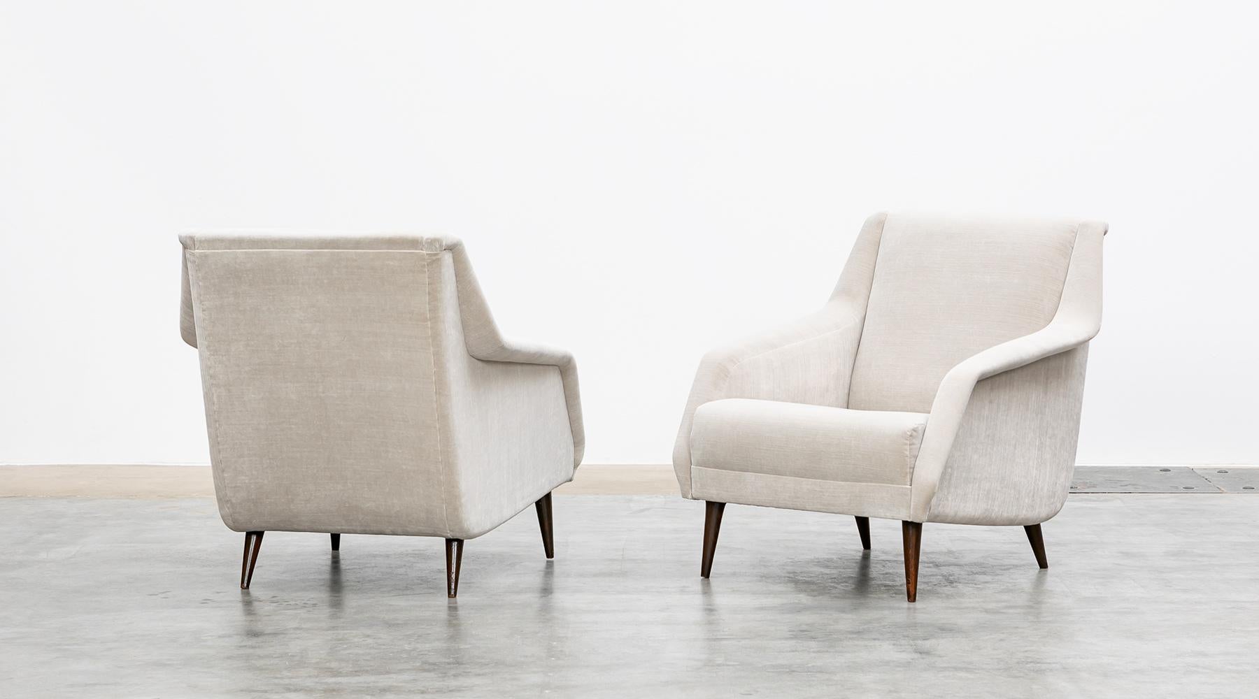 New upholstery in light grey high-quality fabric, lounge chairs by Carlo de Carli, Italy, 1954.

A pair of lounge chairs designed by Carlo de Carli. The sensual curves and elegantly tapering legs give the chairs a sculptural, modern look.