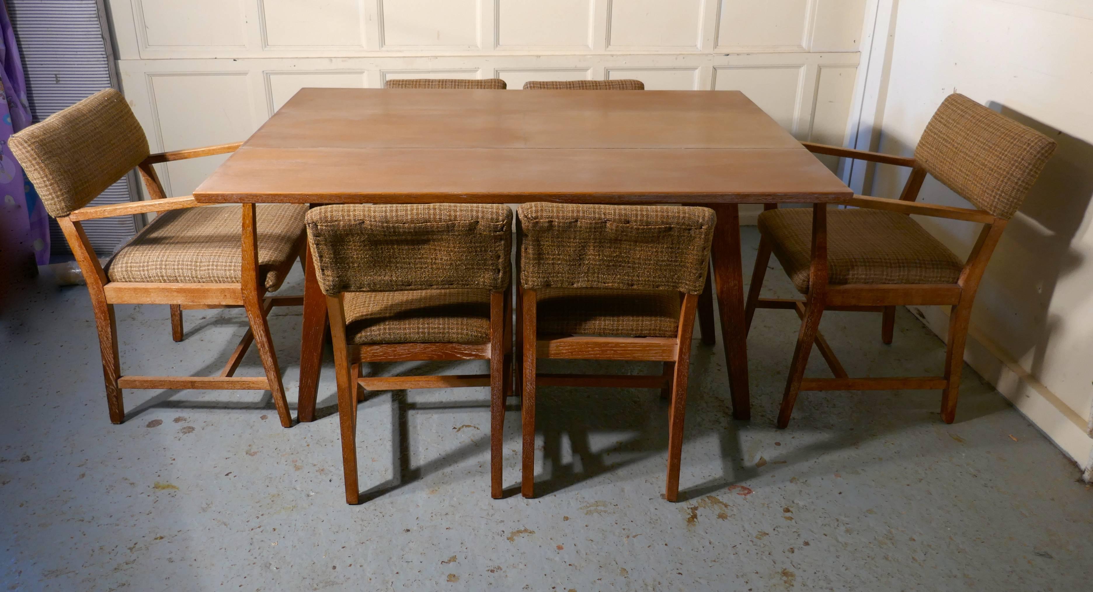 1950s limed oak extending dining table and set of six chairs

A very rare set, the splay legged table pulls apart in the centre allowing a centre leaf to pop up making a small narrow table into large six-seat dining table
The set is in limed oak,
