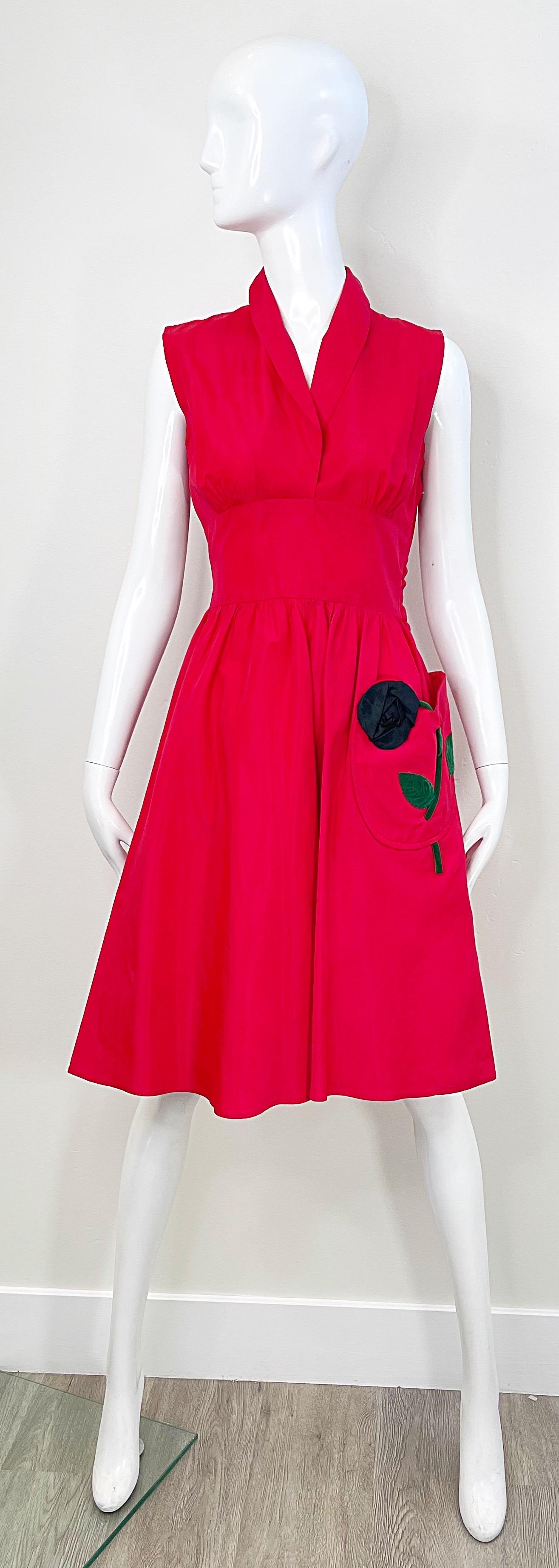 Beautiful and rare vintage 1950s lipstick red silk and nylon taffeta fit and flare dress !  Tailored bodice with a full skirt that features a black taffeta rose with green velvet stem on the pocket. Hidden metal zipper up the side. 
Very well ell