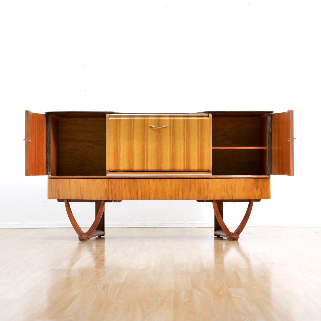 Este mueble credenza de mediados de siglo fue diseñado y fabricado por Beautility Furniture en Inglaterra durante la década de 1950. Una fantástica pieza vintage que tiene mucho espacio de almacenamiento con tres cajones, armarios y un mueble