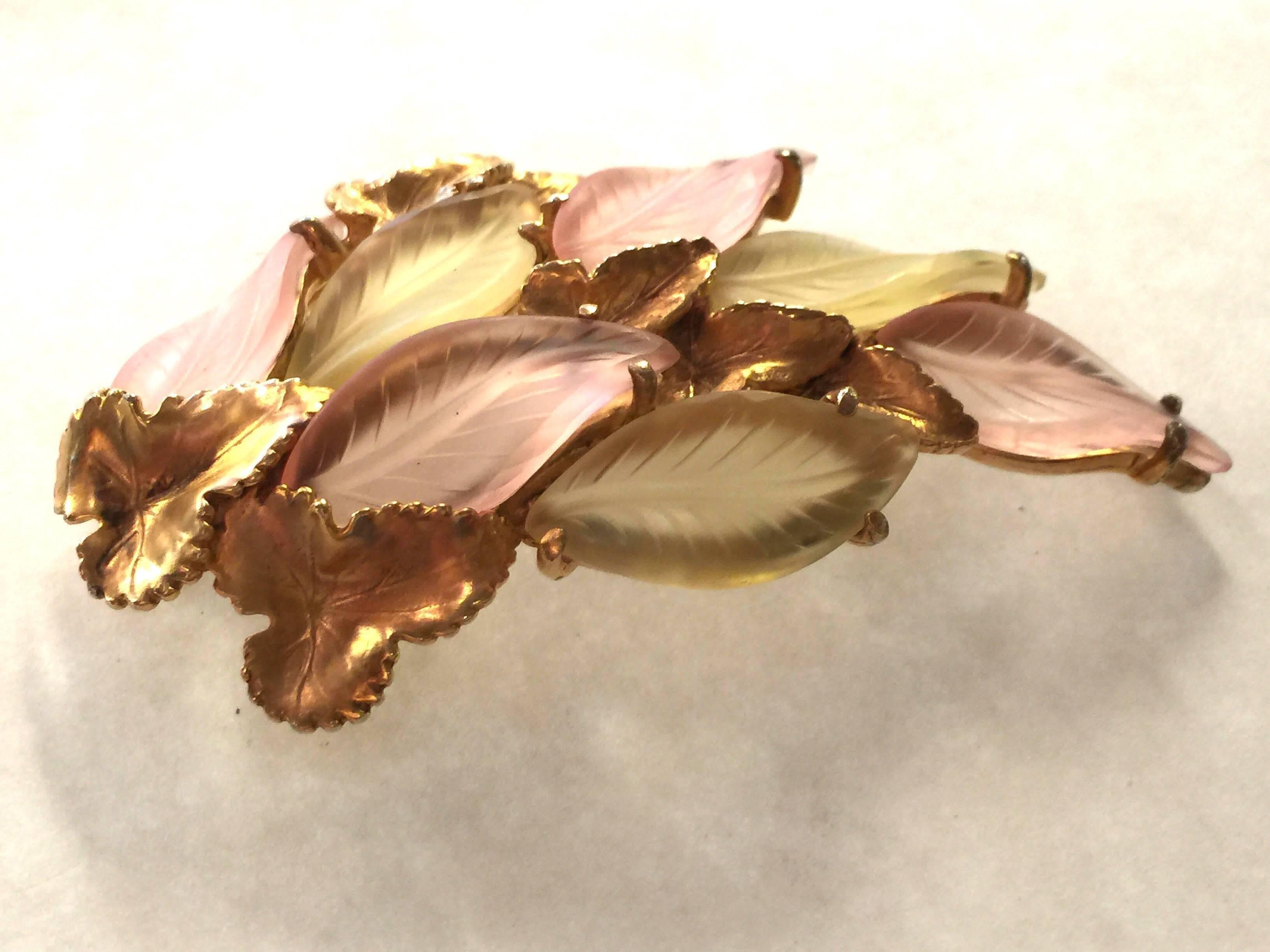 A softly pastel color palette of palest sepia pink and pale frosty yellow set in a brilliant goldtoned romantic Italiante leafy mounting, and set off with highly figural leaf patterning. This is a Schiaparelli pin of unusual design. Reseembling
