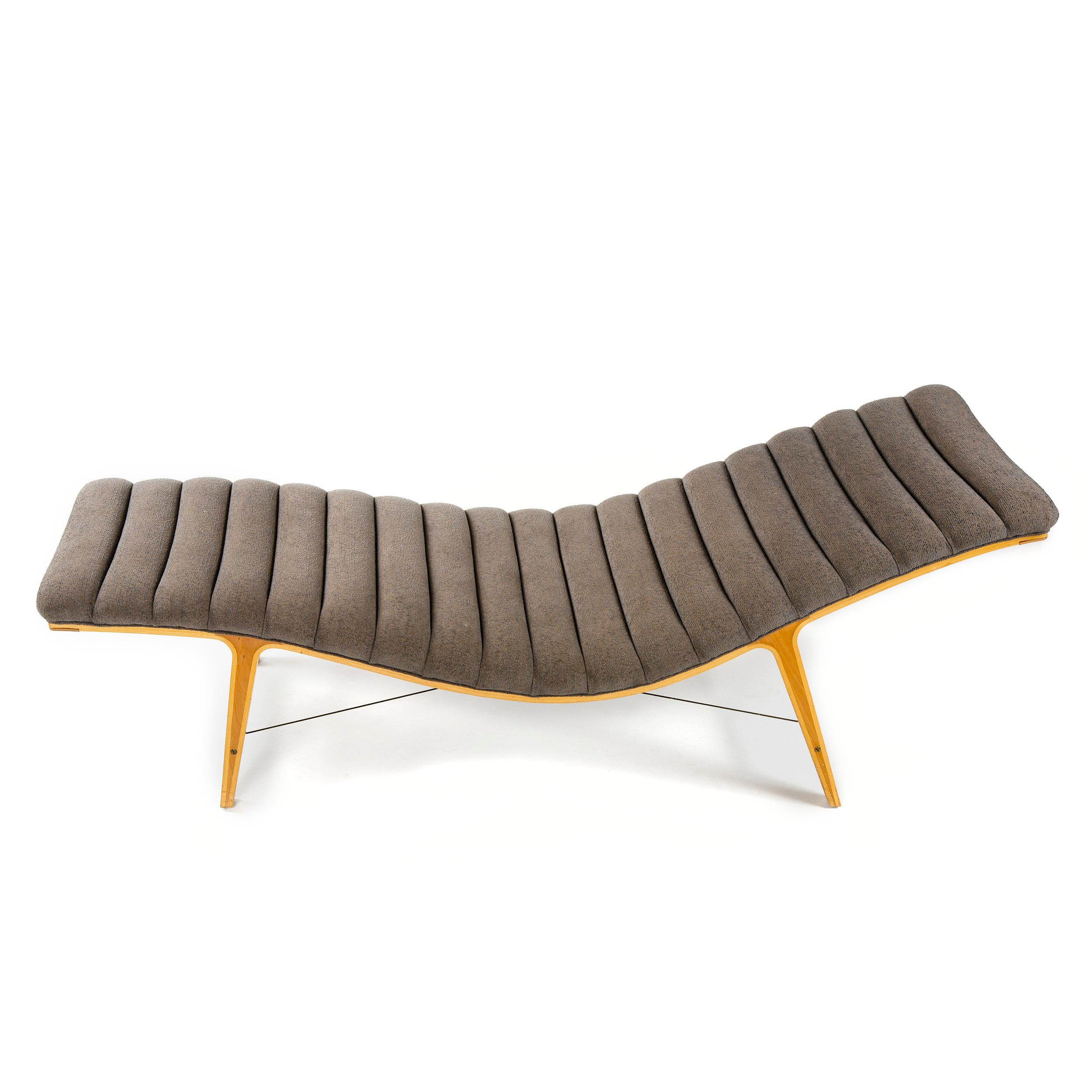 An elegant chaise lounge with an undulating cushion in vintage upholstery with a cherry and maple base and solid brass supports. Model: 4873.
