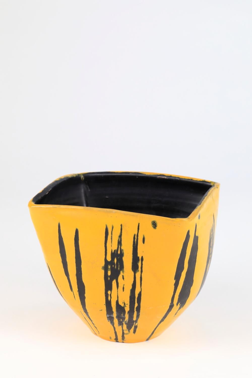 Ce bol en céramique de Livia Gorka se distingue comme une pièce exceptionnelle, incarnant la vision et le savoir-faire uniques de l'artiste. 
La combinaison frappante des teintes noires et jaunes, accentuée par des rayures noires, crée un contraste