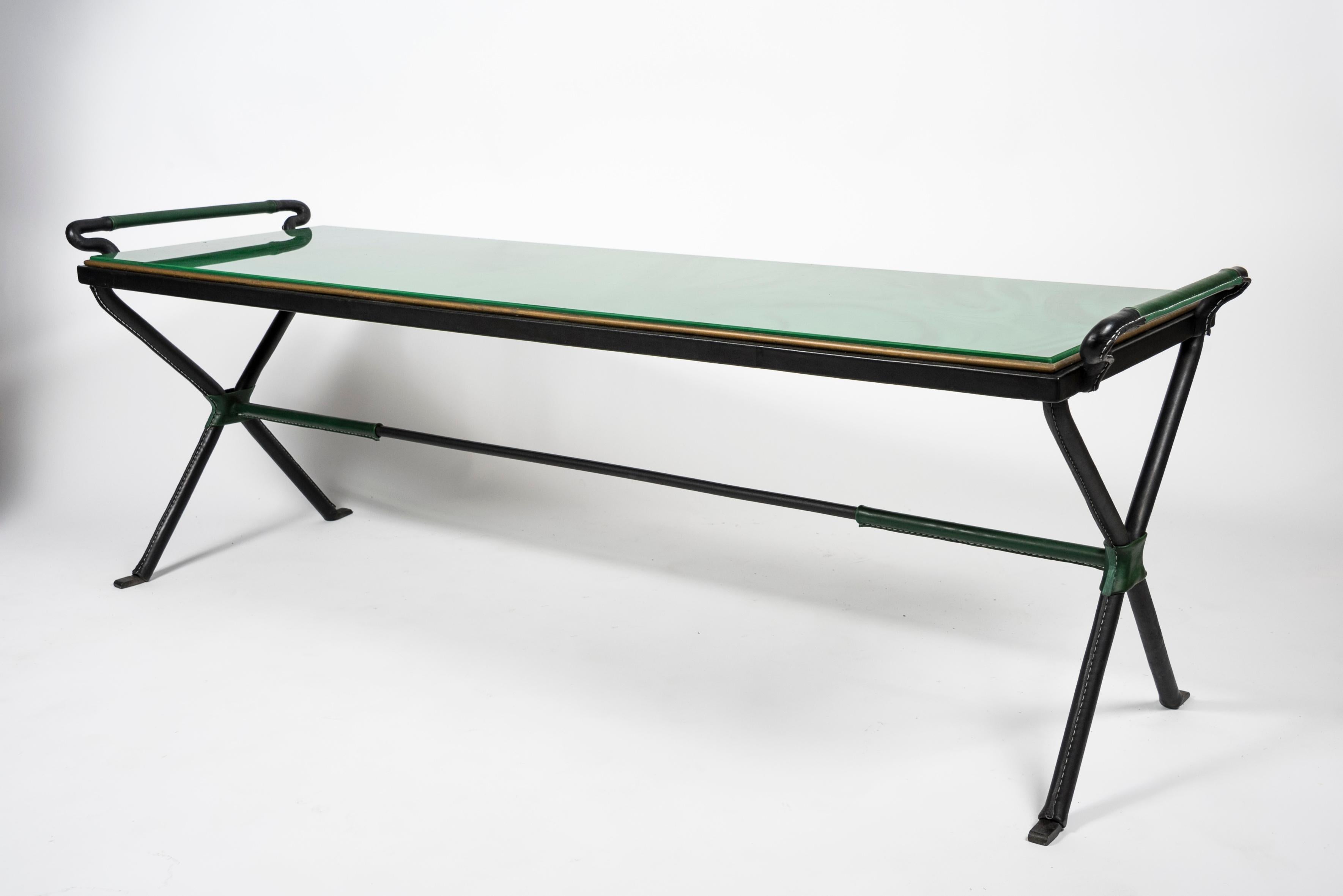 Long stitched leather cocktail table with a stunning green opaline glass.
1950s
France.
