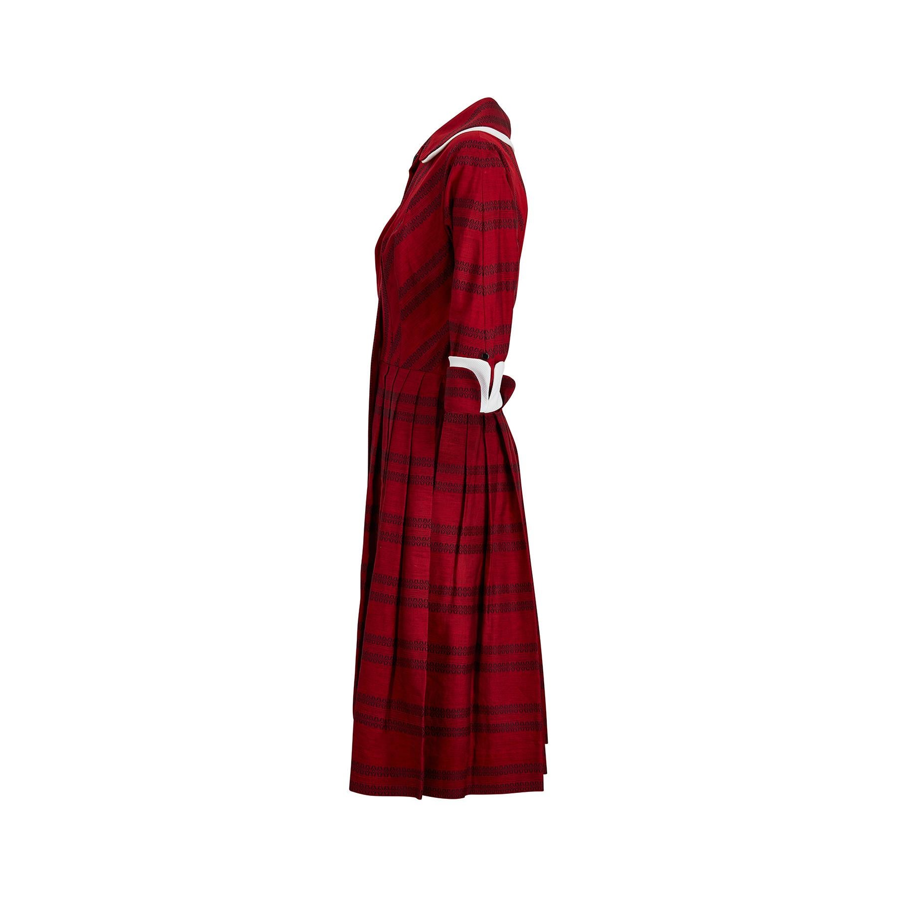 This is a superb and incredibly classic late 1950s shirtwaister dress by Lou-Ette of California. It is made from a beautiful deep burgundy red cotton with a delicate black woven geometric design. The collar and sleeves have a white waffle cotton
