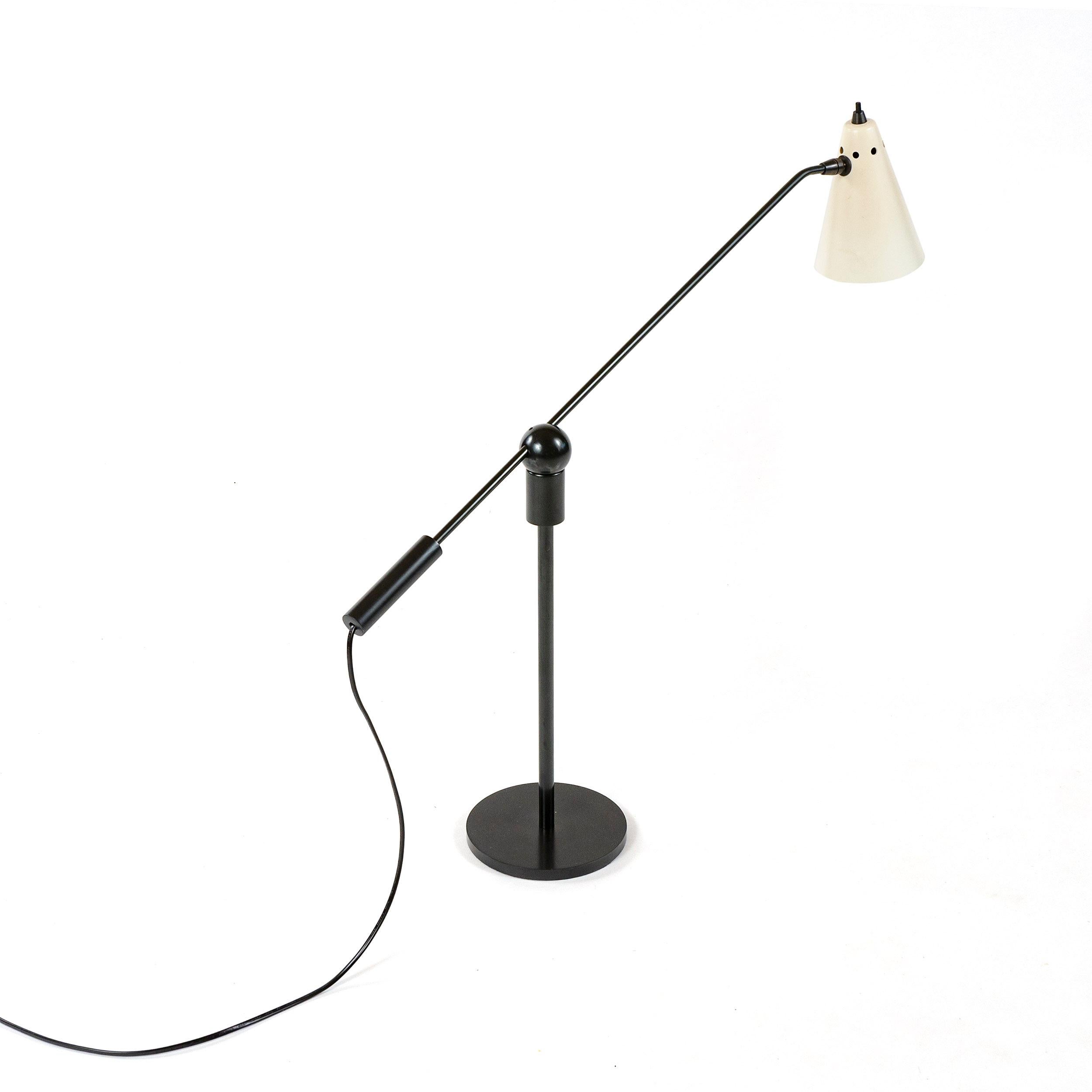 An uncommon patinated steel desk lamp with an adjustable white lacquered conical shade. The arm is attached to a circular magnet ball and socket connection, allowing for a high degree of articulation and movement.
