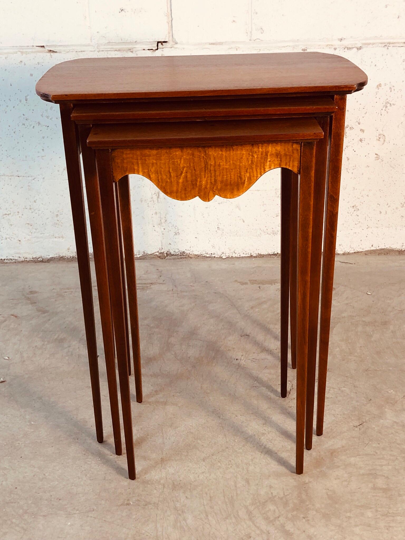 1950s set of 3 mahogany nesting tables with a tiger maple accent. The tables have very thin and delicate legs. No marks. They have been refinished and restored. The top table does still have a lighter stain that shows in the photos.