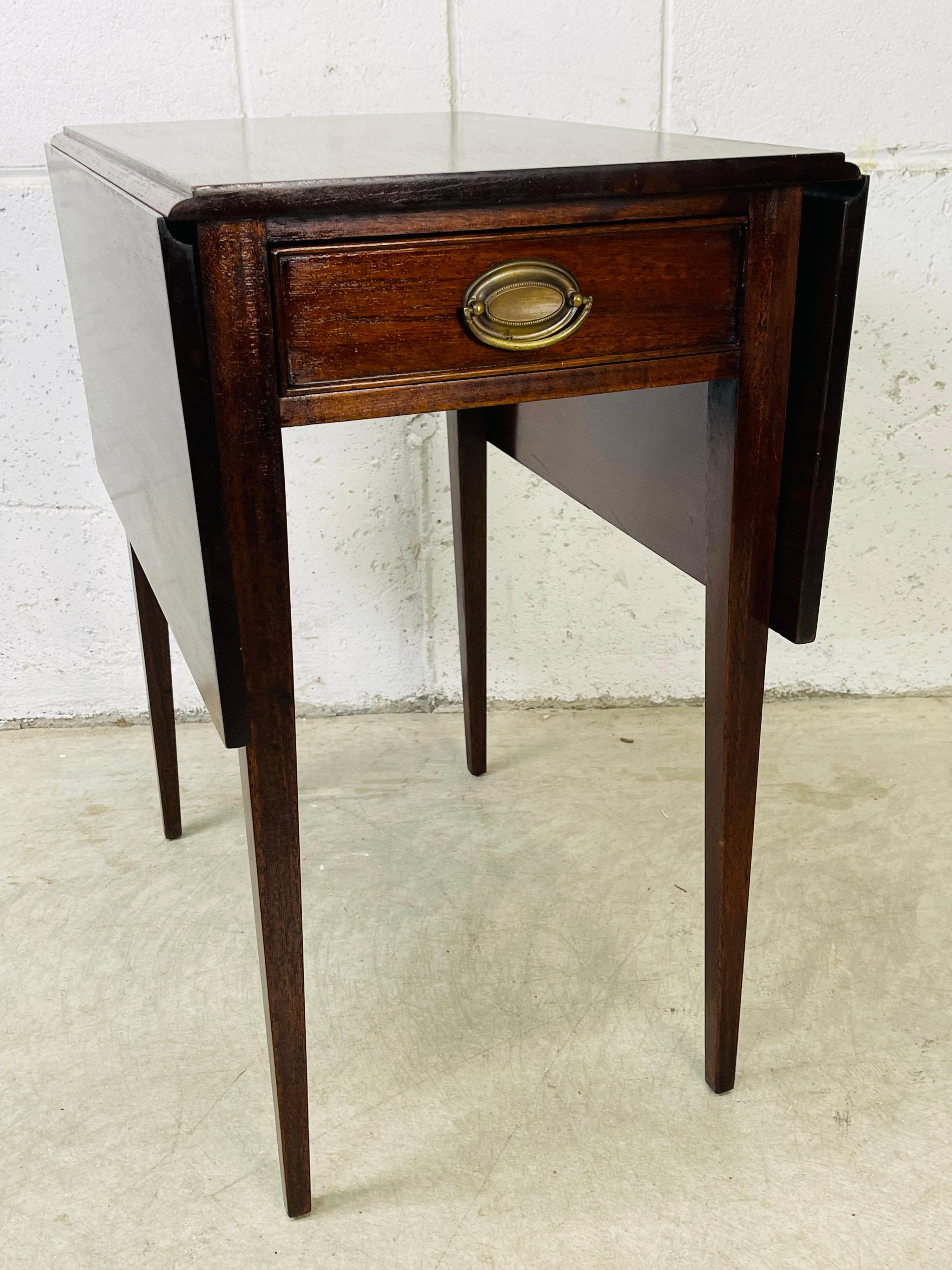 Beistelltisch aus Mahagoniholz der 1950er Jahre mit konischen Beinen. Der Tisch hat eine einzelne Schublade mit einem Messinggriff. Die Klappseiten lassen sich öffnen, um den Tisch zu erweitern. Vollständig geöffnet ist der Tisch 34,75